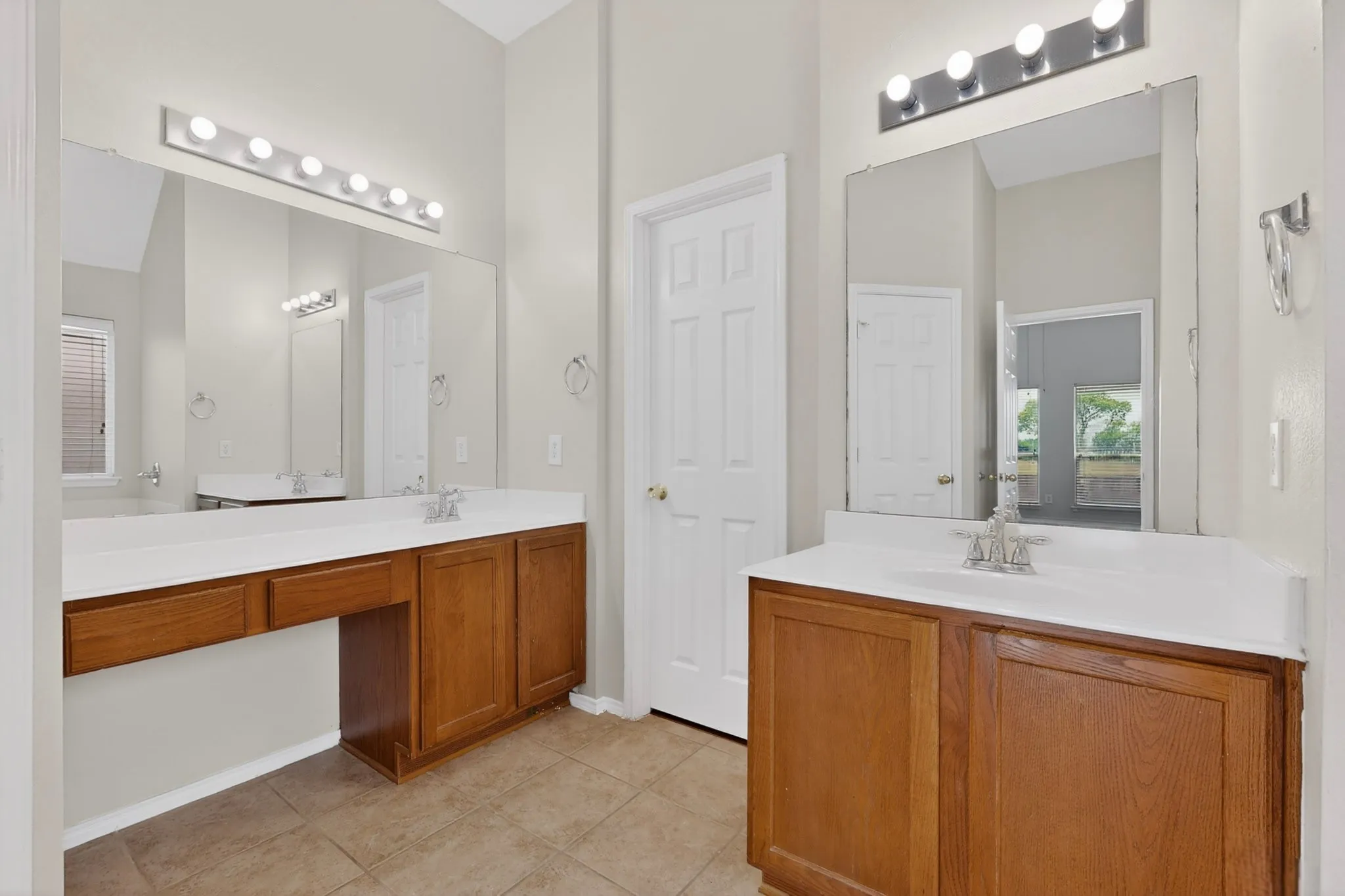 Double vanity featuring wood-finish cabinetry, integrated white sinks, and chrome fixtures