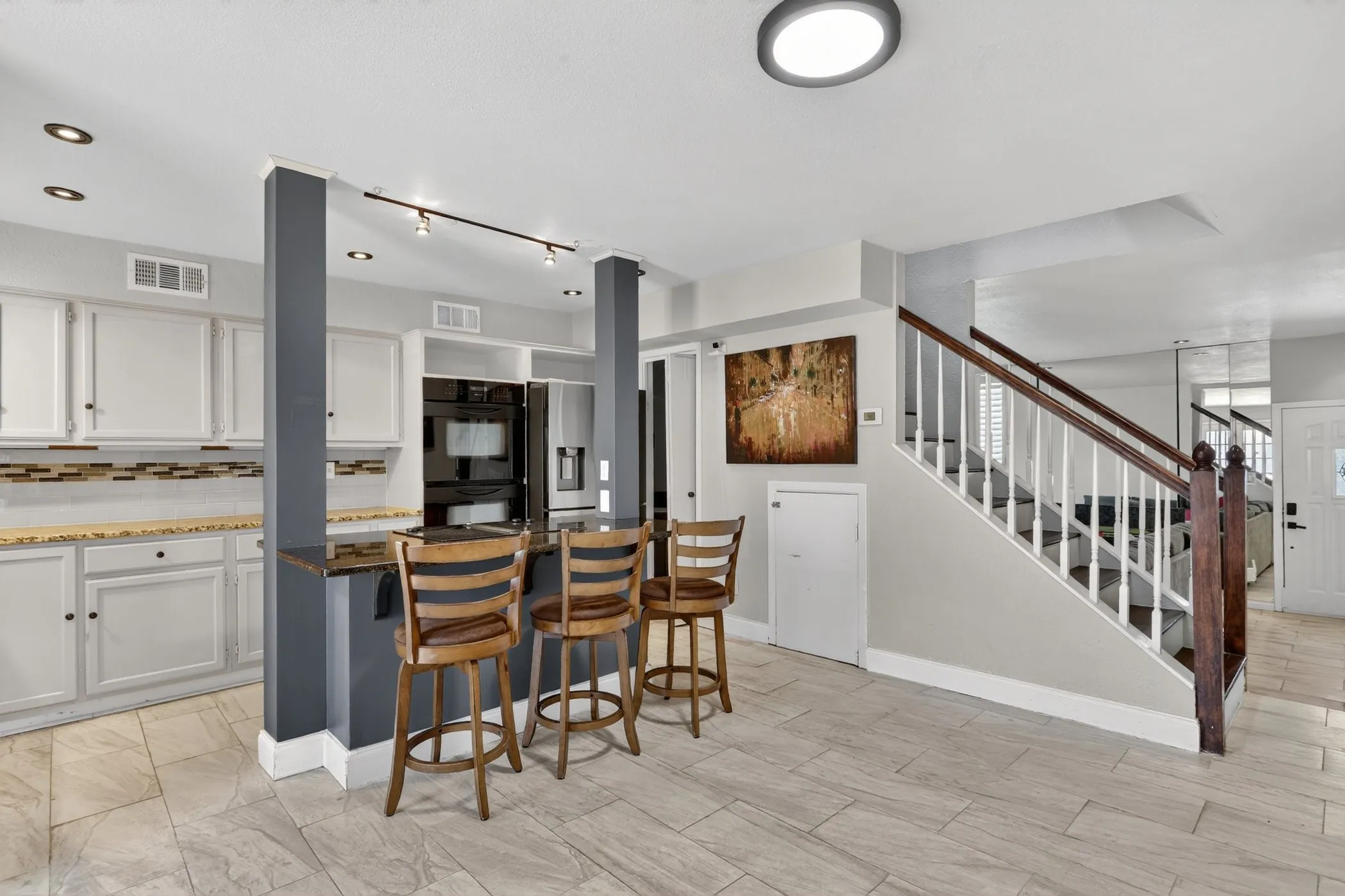 Kitchen with white cabinetry, a tiled backsplash, and dark built-in appliances