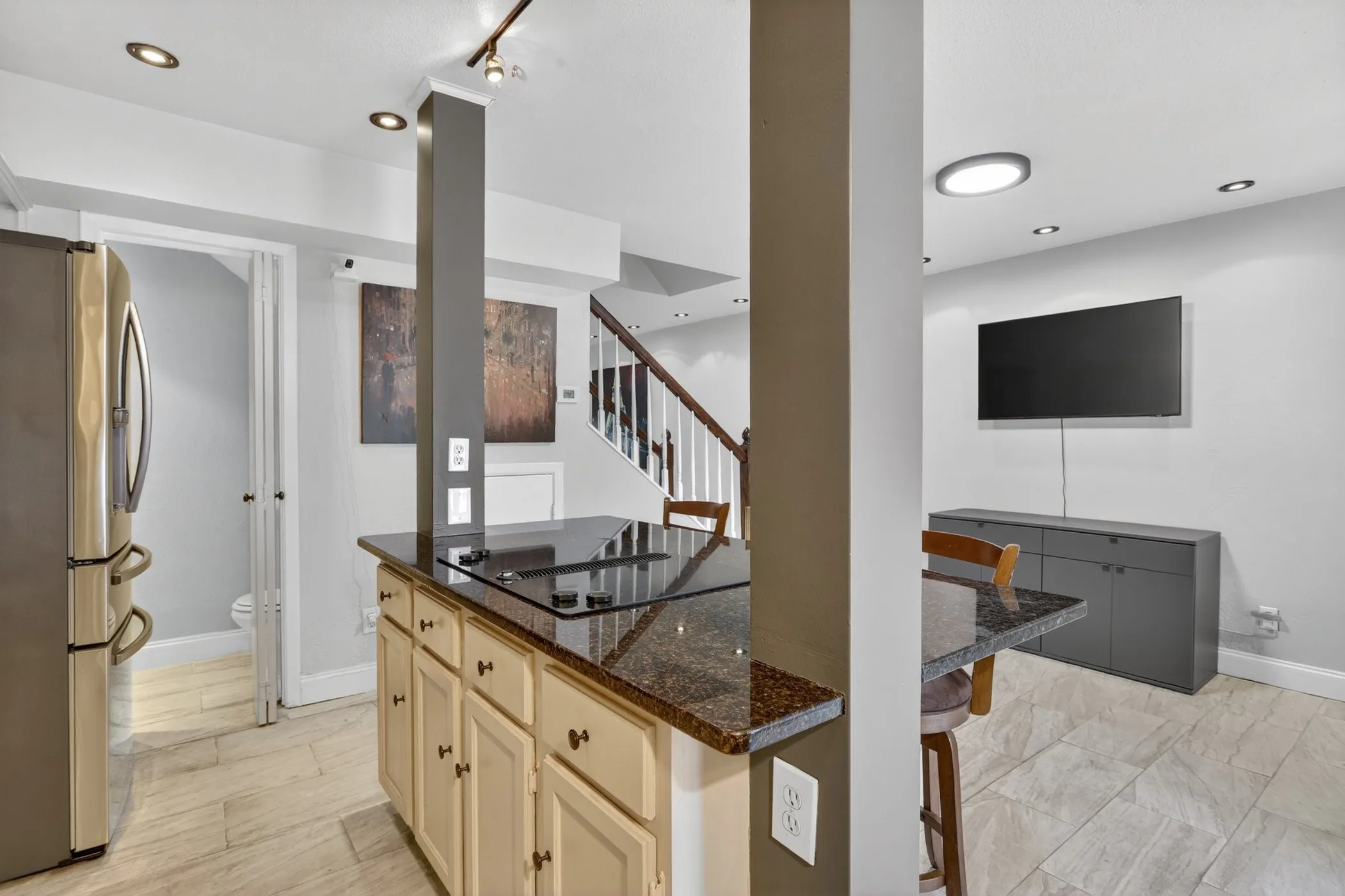 Kitchen island with a built-in cooktop and stone-finish countertop, flanked by painted cabinetry