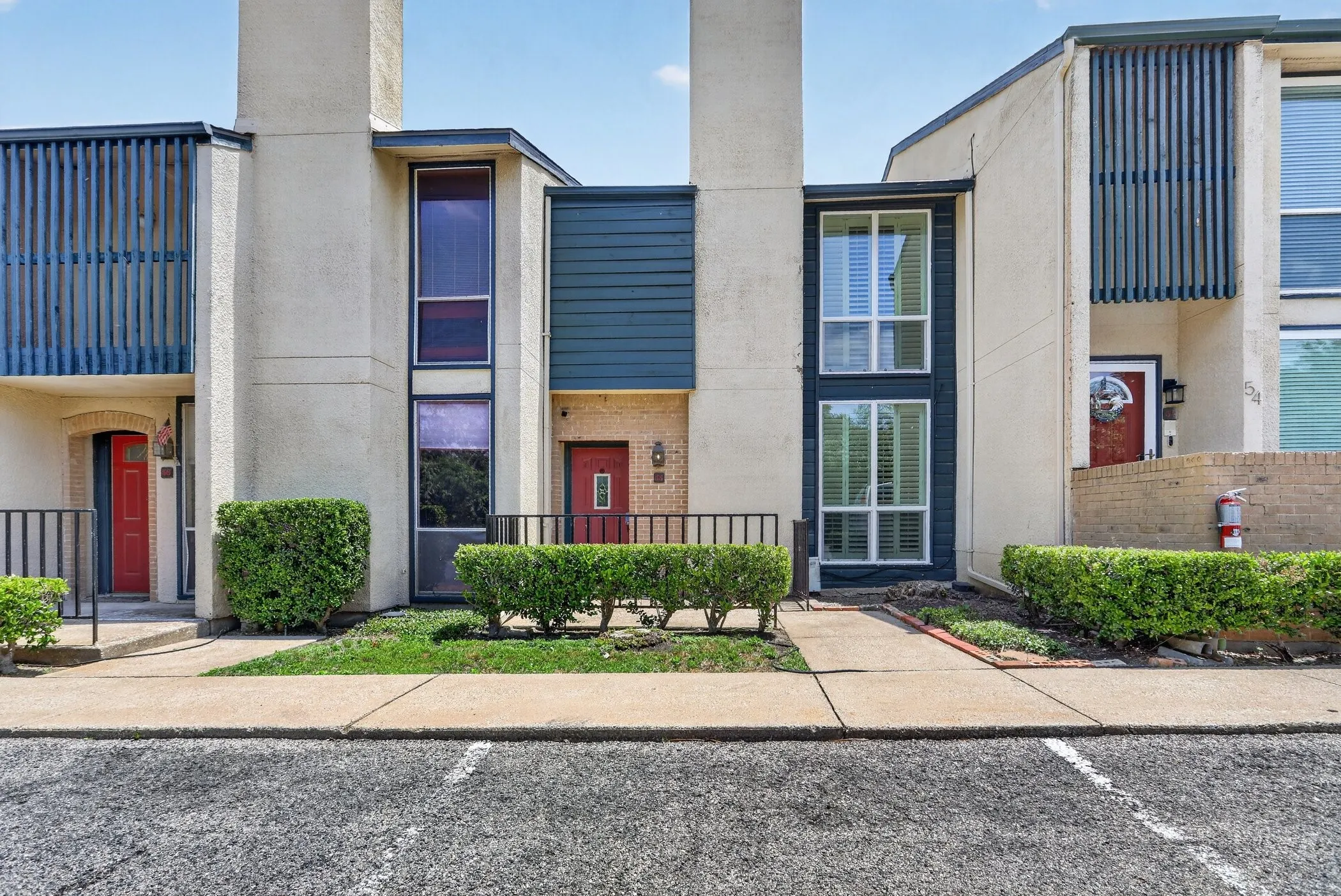 Modern stucco exterior featuring vertical siding accents and multiple red entry doors