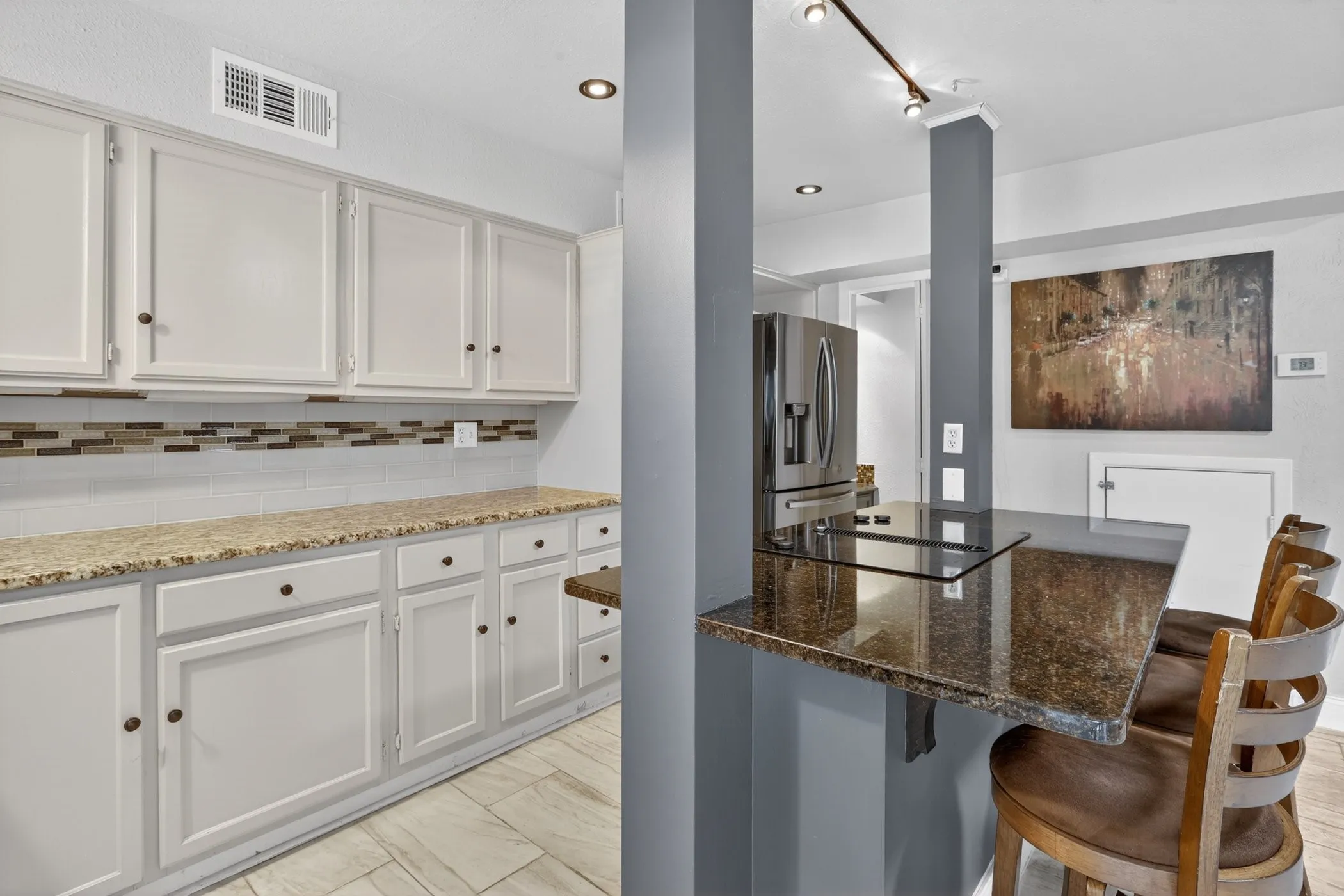 Kitchen featuring white shaker-style cabinetry, mosaic tile backsplash, and light-toned countertops