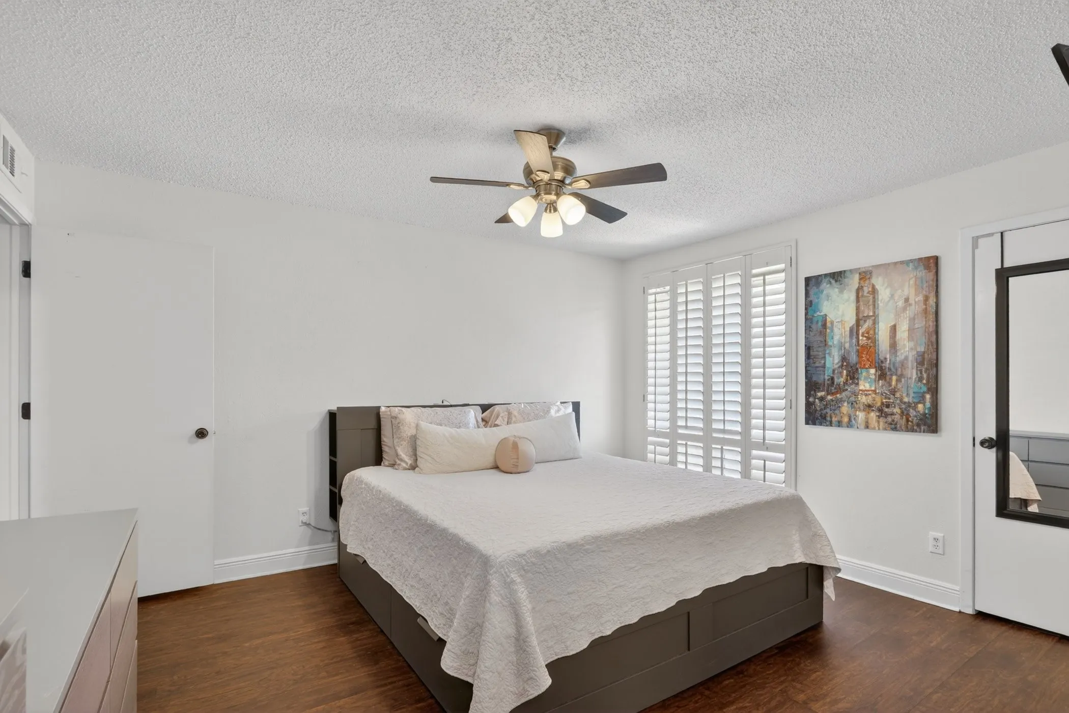 Spacious room featuring wood-finish flooring, white walls, and a ceiling fan with integrated lighting