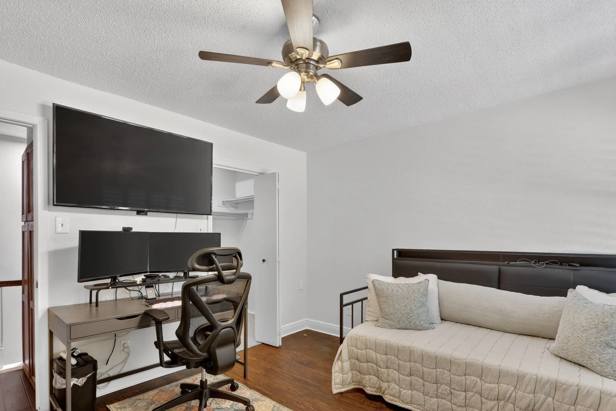 Interior room featuring wood-finish flooring, a ceiling fan with integrated lighting, and white painted walls