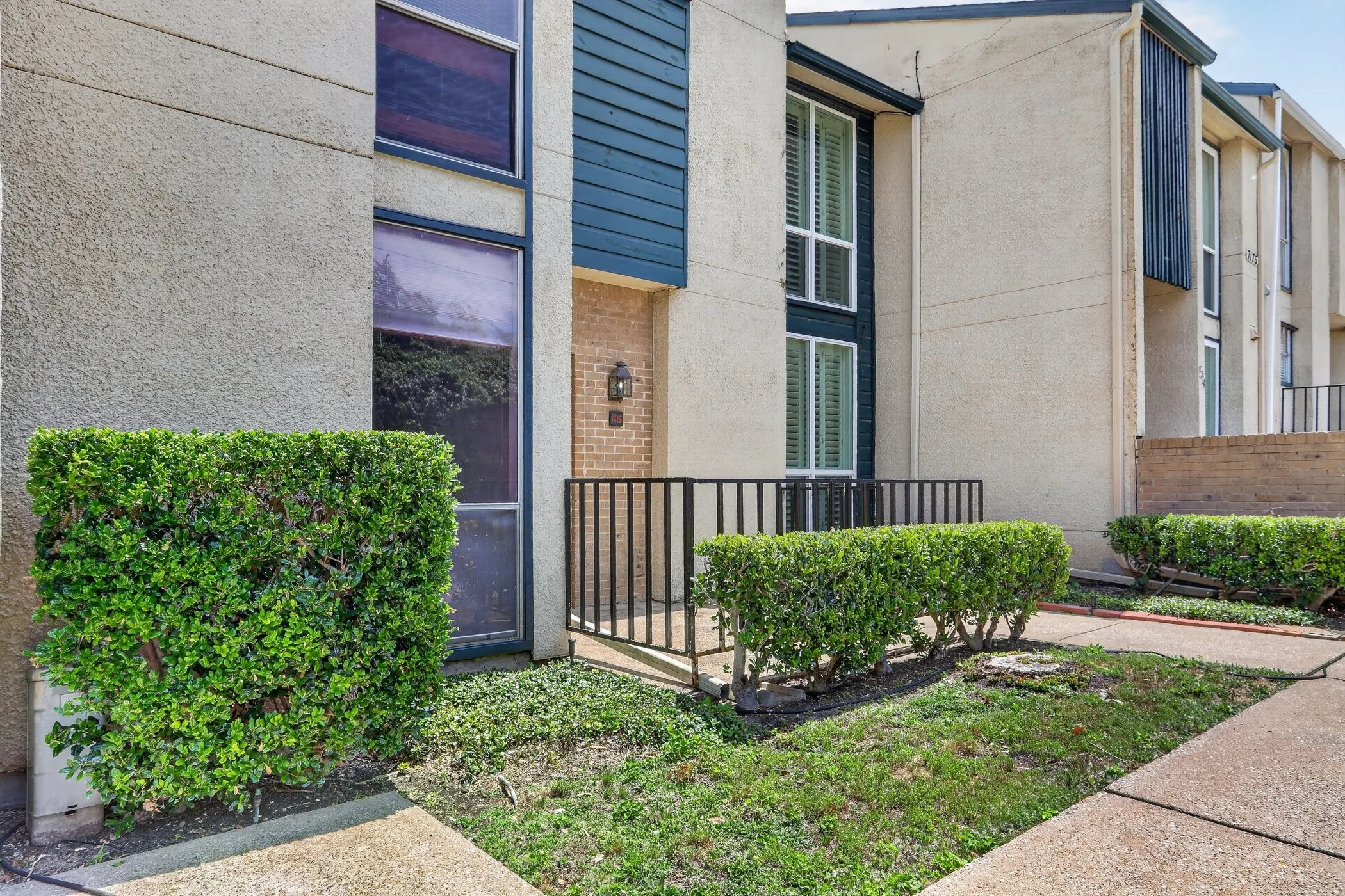 Exterior facade featuring stucco siding, vertical dark blue paneling, and a brick entrance accent