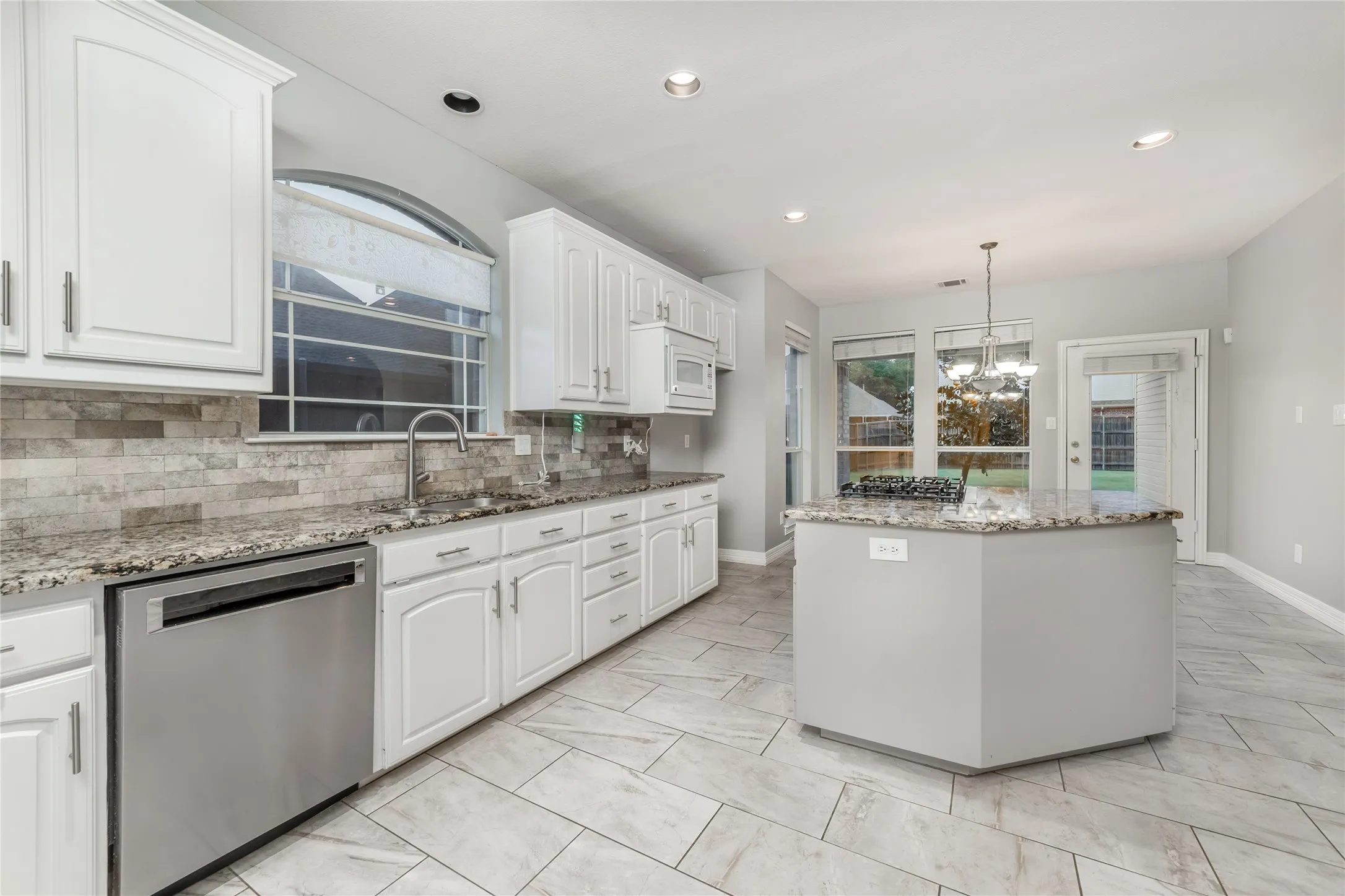 Kitchen featuring white cabinetry, stainless steel appliances, granite countertops, and a tiled backsplash