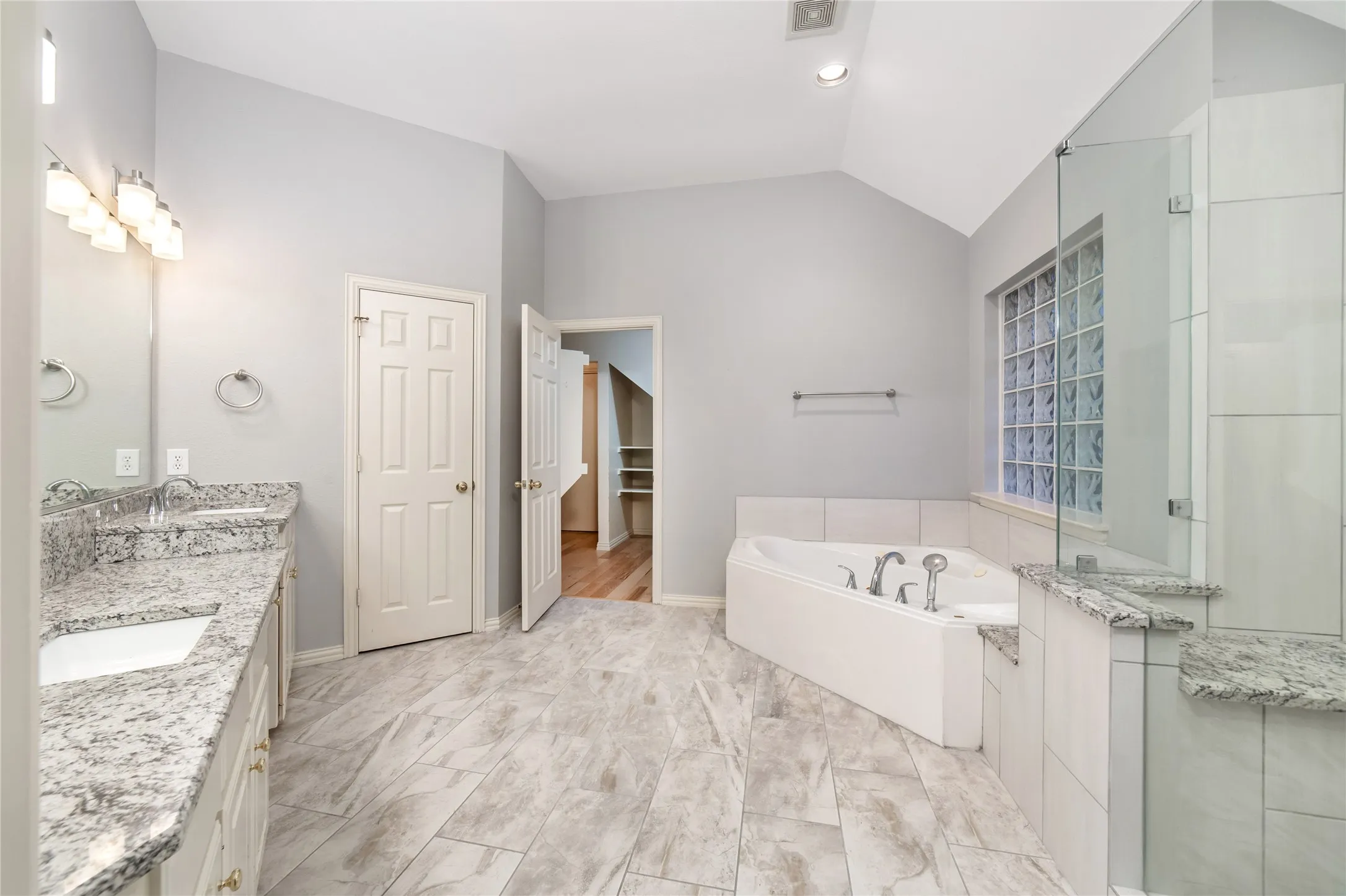 Spacious bathroom featuring a vaulted ceiling and tile flooring