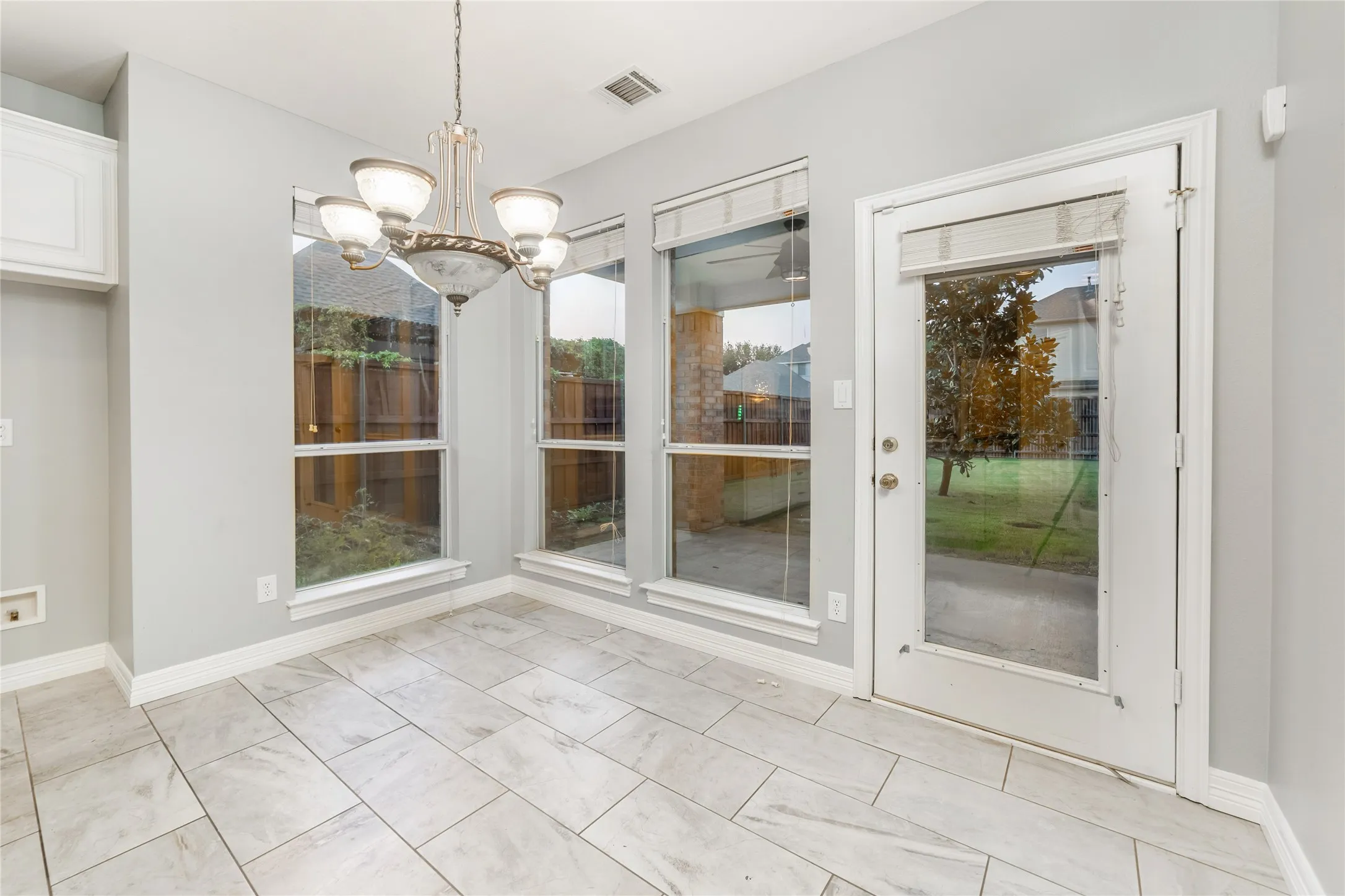 Tiled flooring complements a classic chandelier in this bright interior space