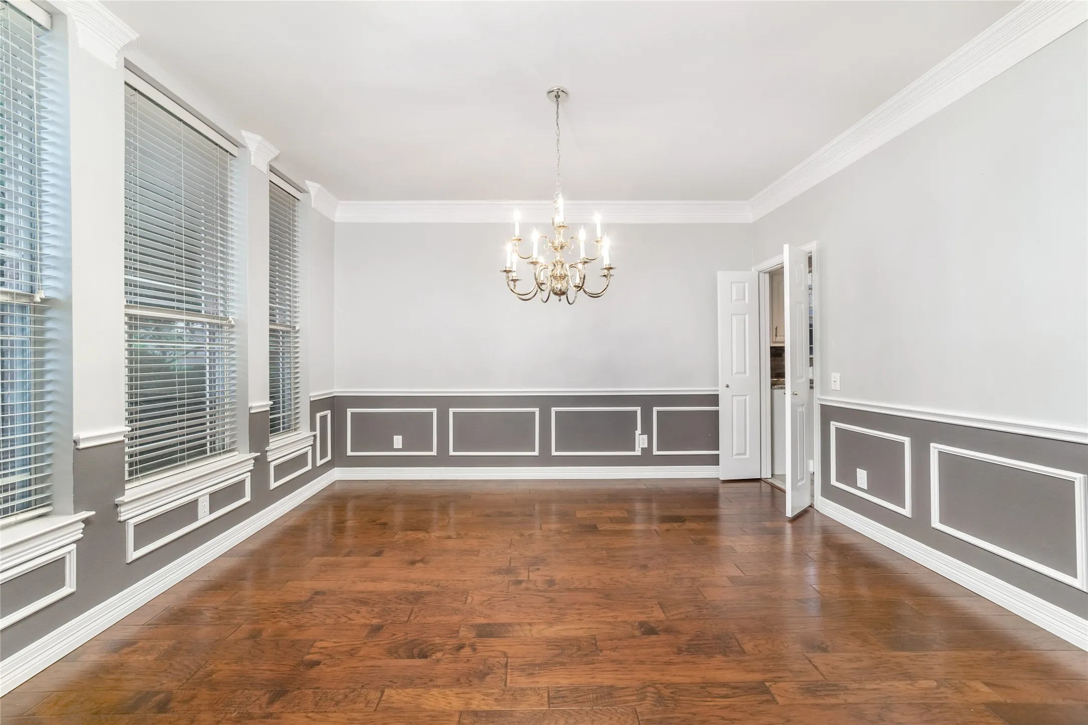 Formal dining area featuring rich wood-finish flooring, a decorative chandelier, and extensive crown molding