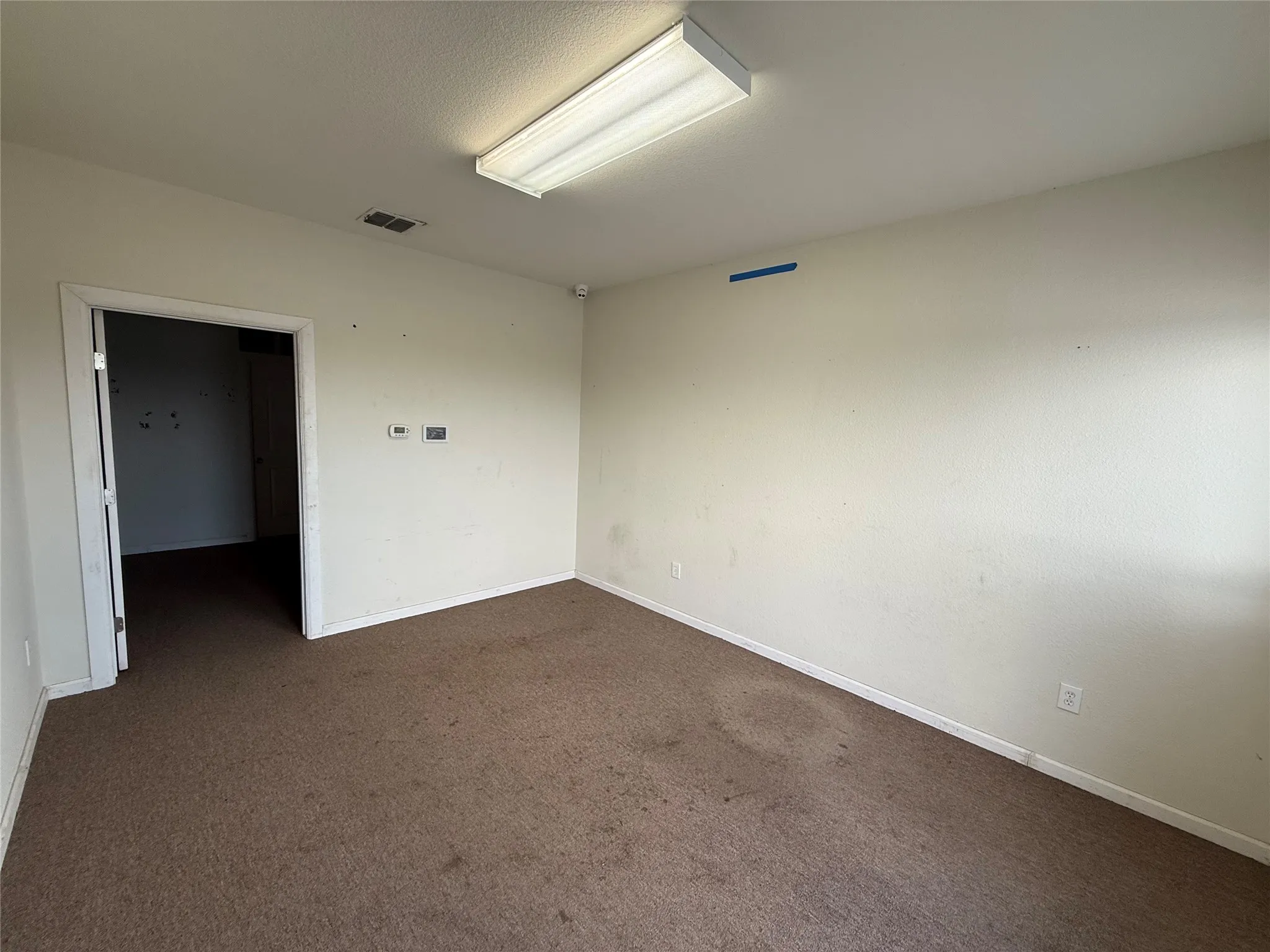 Room featuring carpet flooring, white painted walls, and a fluorescent ceiling light fixture