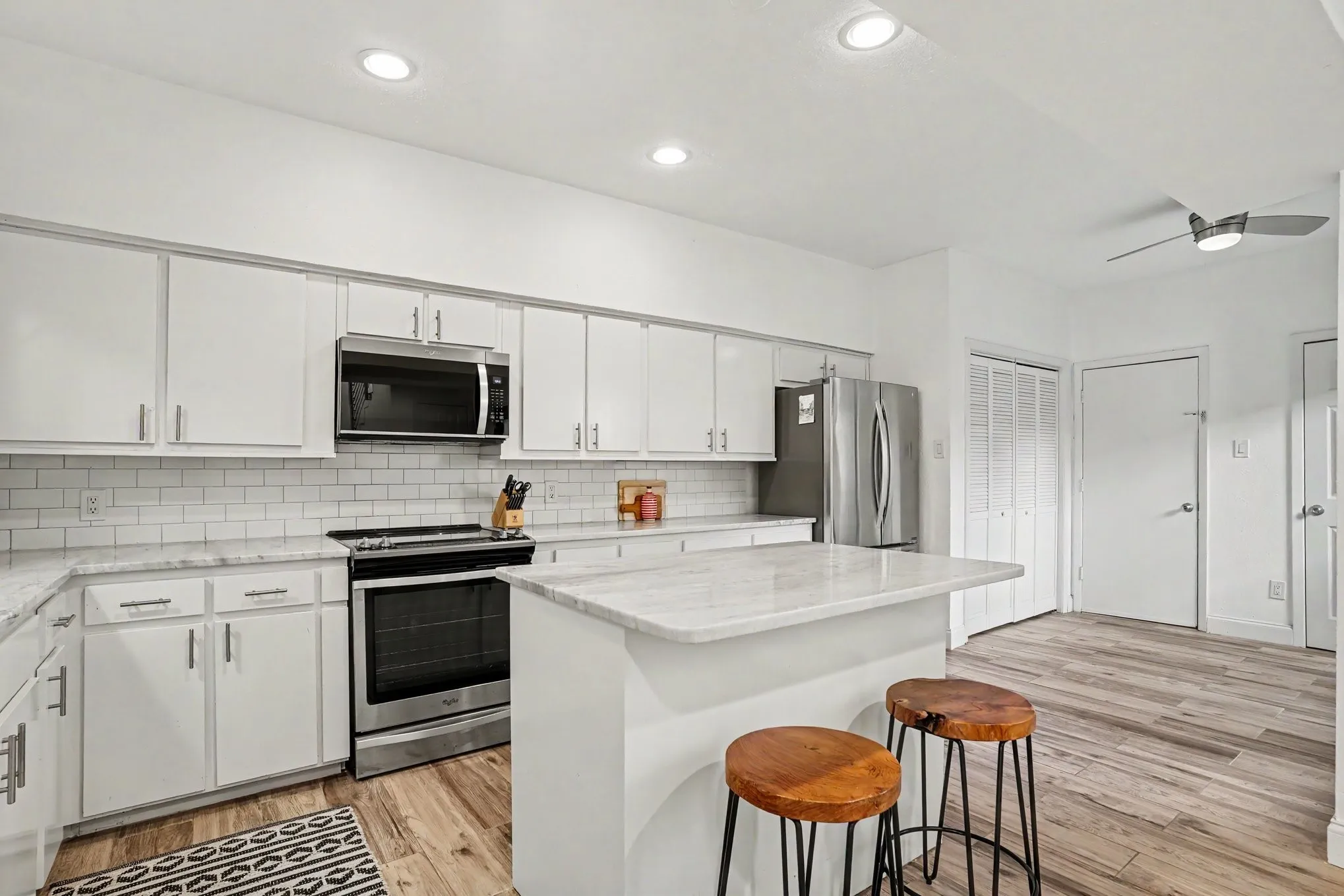 Modern kitchen featuring white cabinetry, subway tile backsplash, stainless steel appliances, and a central island with countertop seating