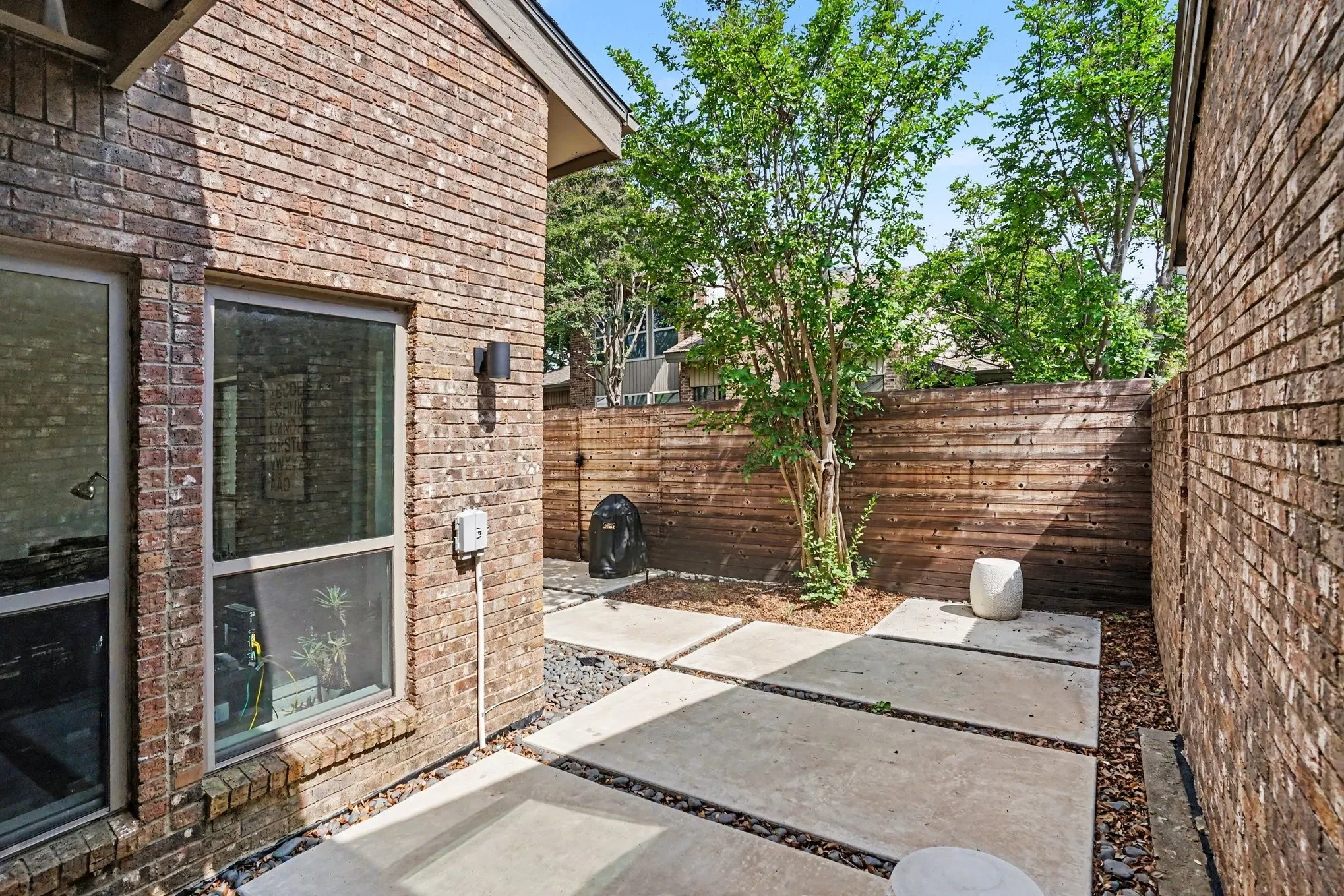 Private outdoor space featuring large format pavers, decorative gravel, and a wood privacy fence