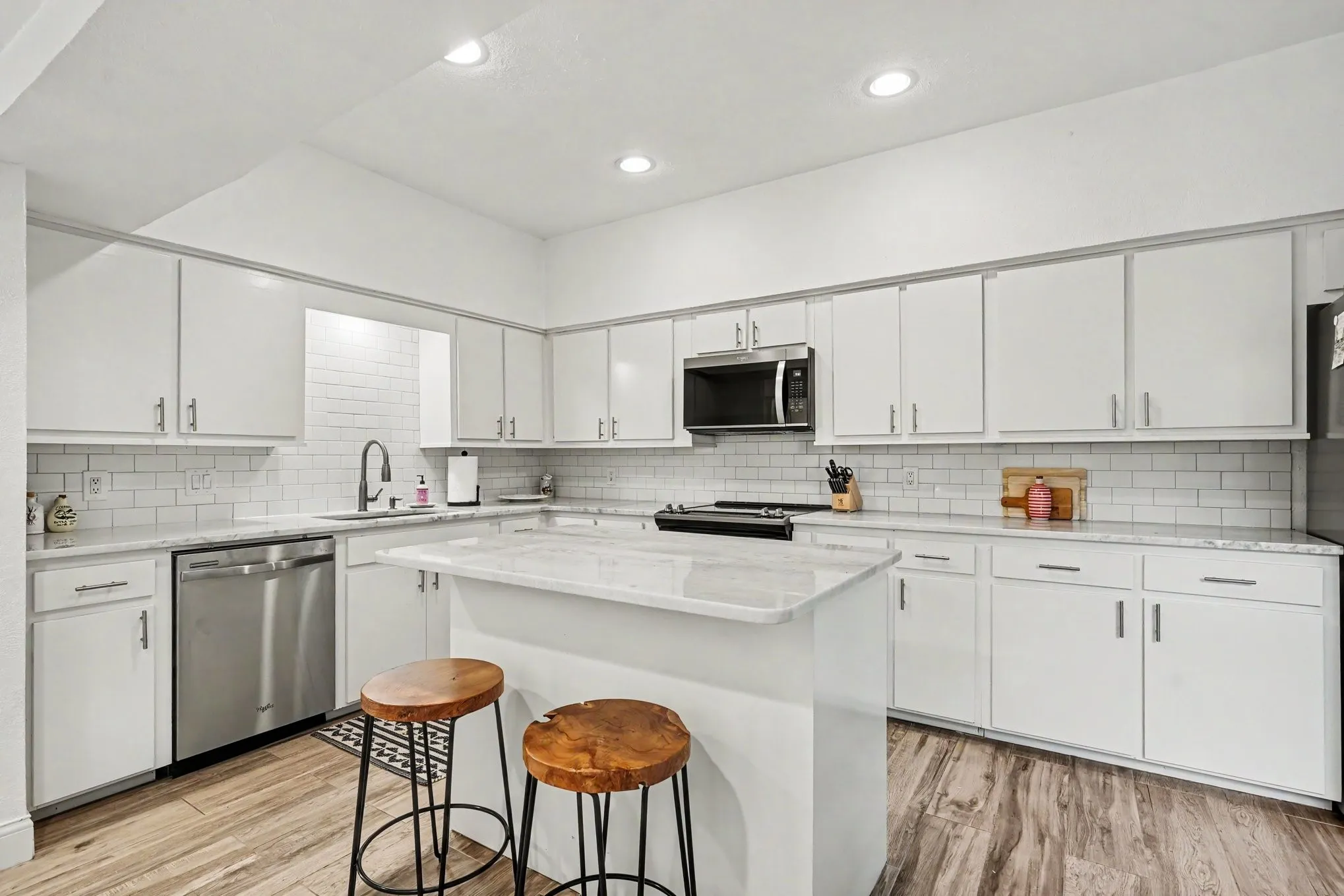 Kitchen featuring white cabinetry, subway tile backsplash, stainless steel appliances, recessed lighting, and wood-finish flooring