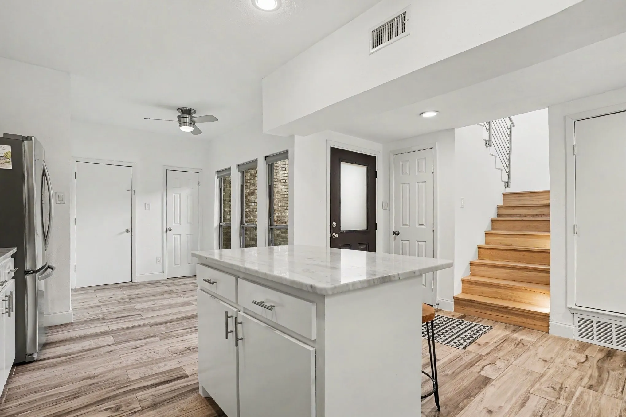 Kitchen island featuring a light-toned countertop, wood-finish flooring, and white cabinetry