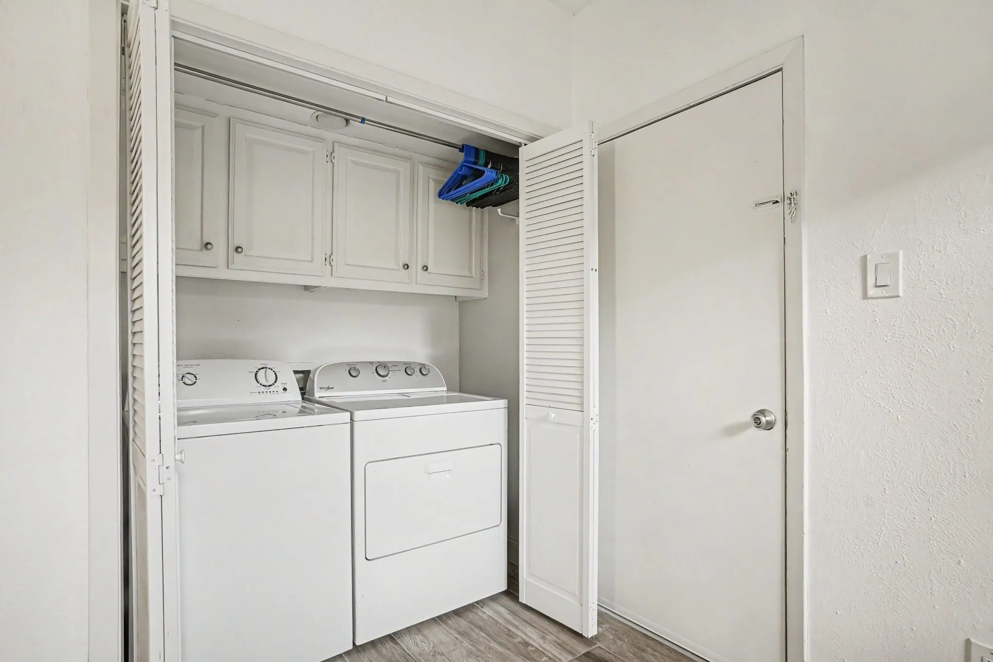 Dedicated laundry closet featuring a white washing machine, white dryer, and upper cabinetry for storage