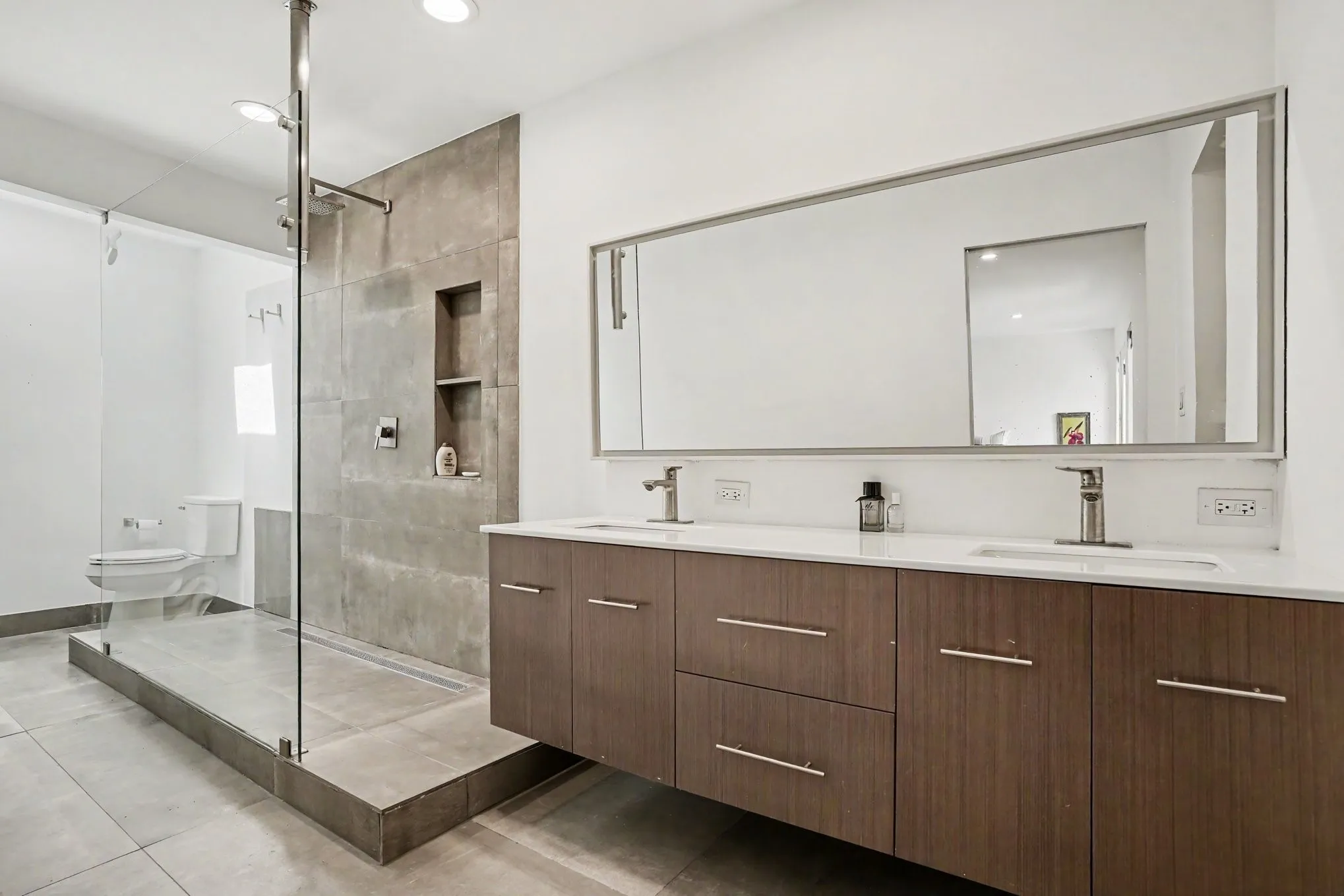 Double vanity with wood-finish cabinetry, white countertops, and dual vessel sinks