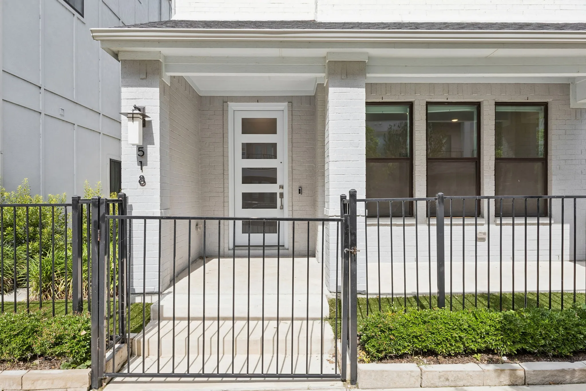 Gated Front Porch Welcome
A fenced front courtyard and covered porch create a welcoming transition from the sidewalk to the home’s private entry.