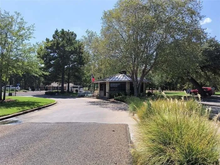 Gated community entrance featuring a stone-clad guardhouse with a metal roof