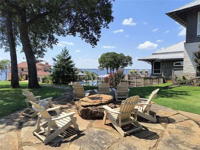 Flagstone patio with a built-in stone fire pit, surrounded by a manicured lawn and mature trees