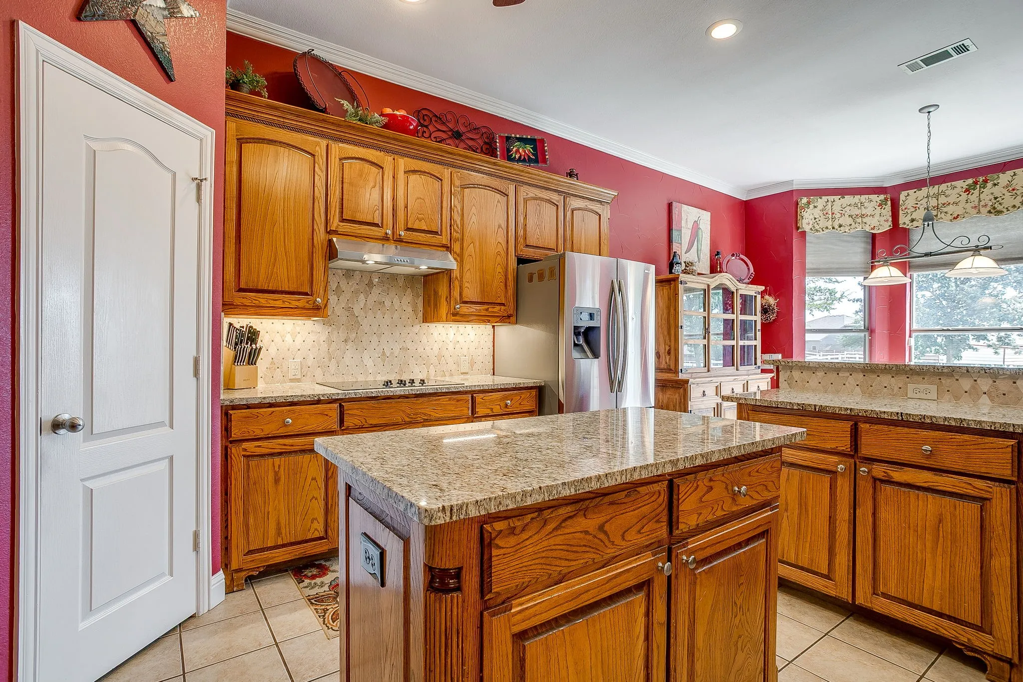 Kitchen featuring wooden cabinetry, granite countertops, a central island, stainless steel appliances, and tile flooring