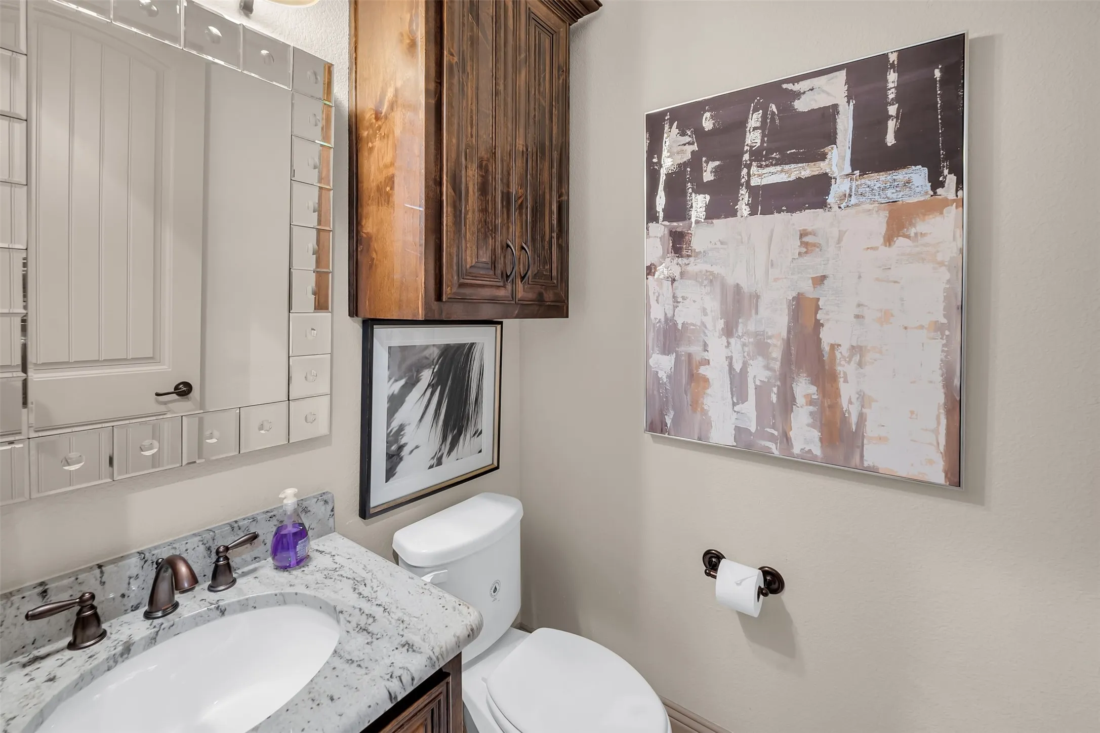 Bathroom vanity featuring a white oval sink, bronze-finish faucet, and granite countertop