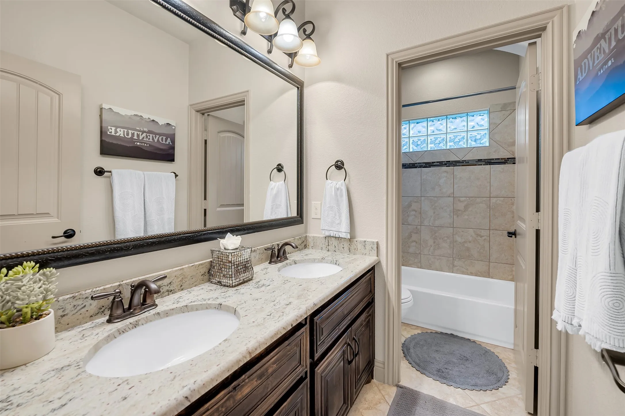 Dual vanity with granite countertop and undermount sinks, bronze-finish fixtures, and a large framed mirror