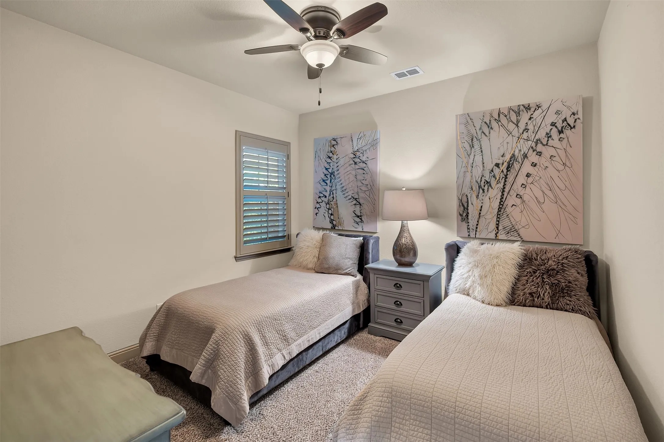 Bedroom featuring light neutral wall paint, a ceiling fan with integrated lighting, a window with louvered shutters, and carpet flooring