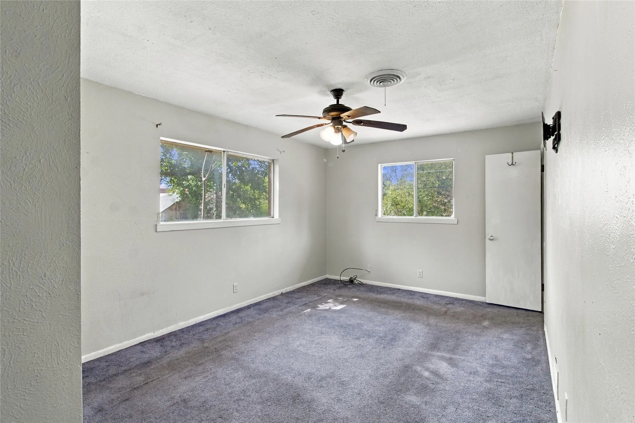 Dual pane windows, ceiling fan with integrated lighting, wall-mounted television bracket, and light gray wall paint