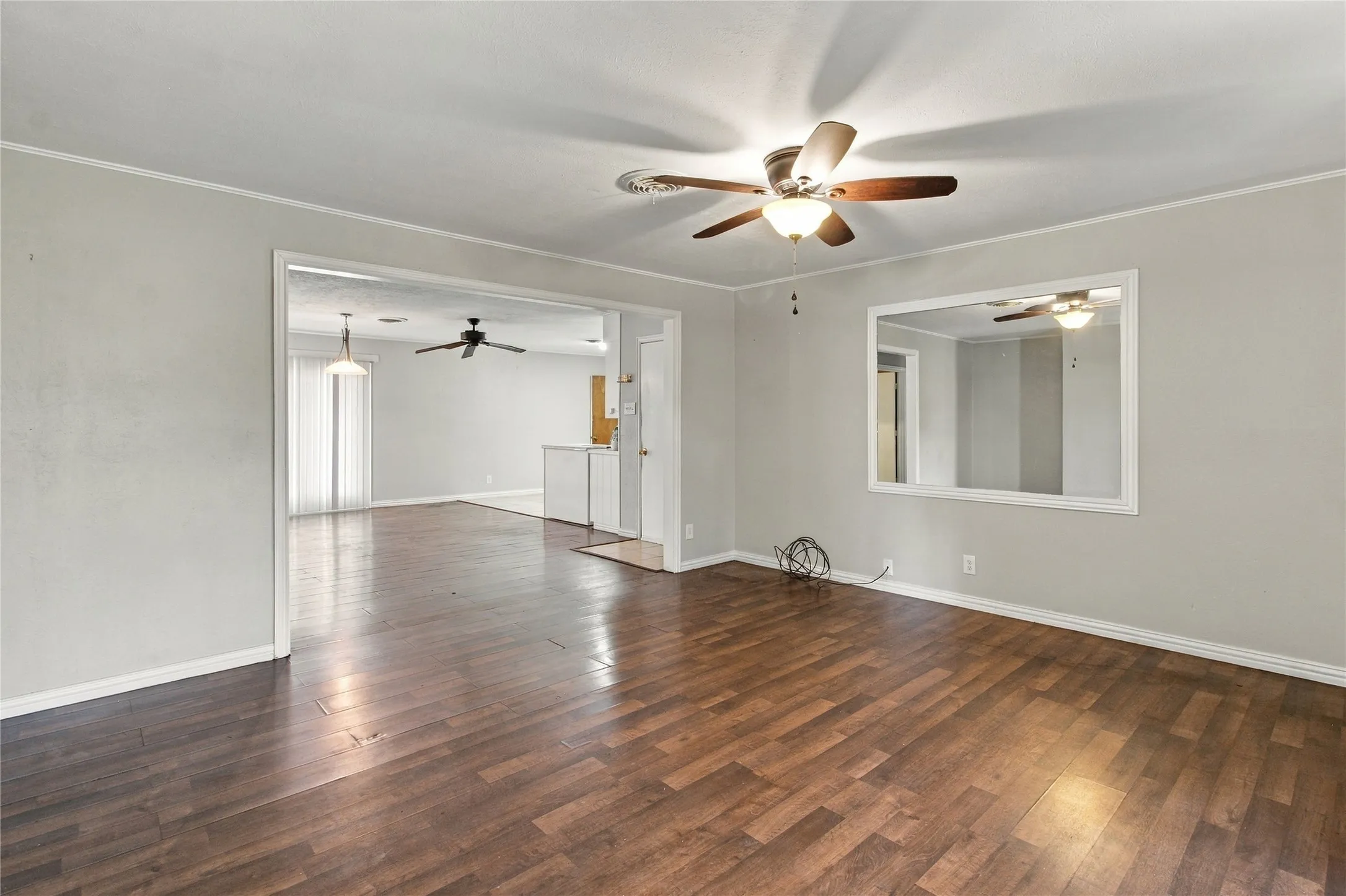 Wood-finish flooring throughout, light gray wall color, and a ceiling fan with integrated lighting