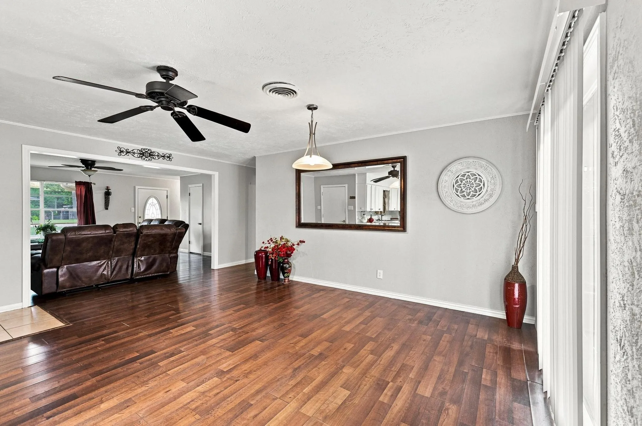 Wood-finish flooring, ceiling fan, contemporary pendant lighting, and vertical blinds