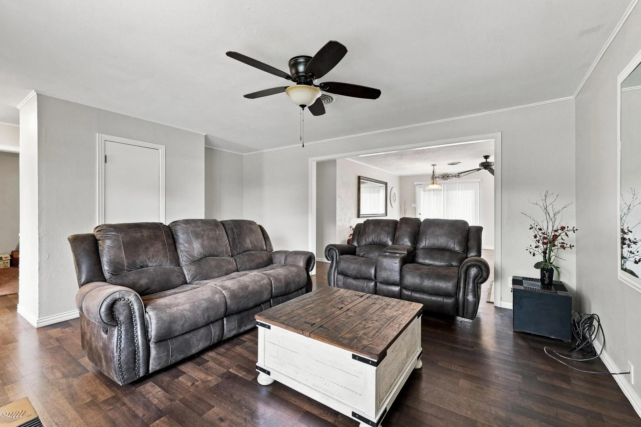 Wood-finish flooring, ceiling fan, white trim, and light gray walls