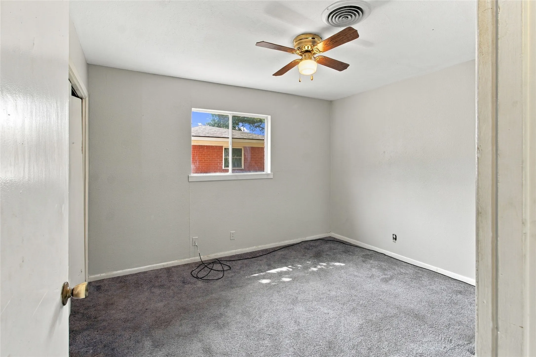 Neutral wall paint with window, ceiling fan, and grey carpet