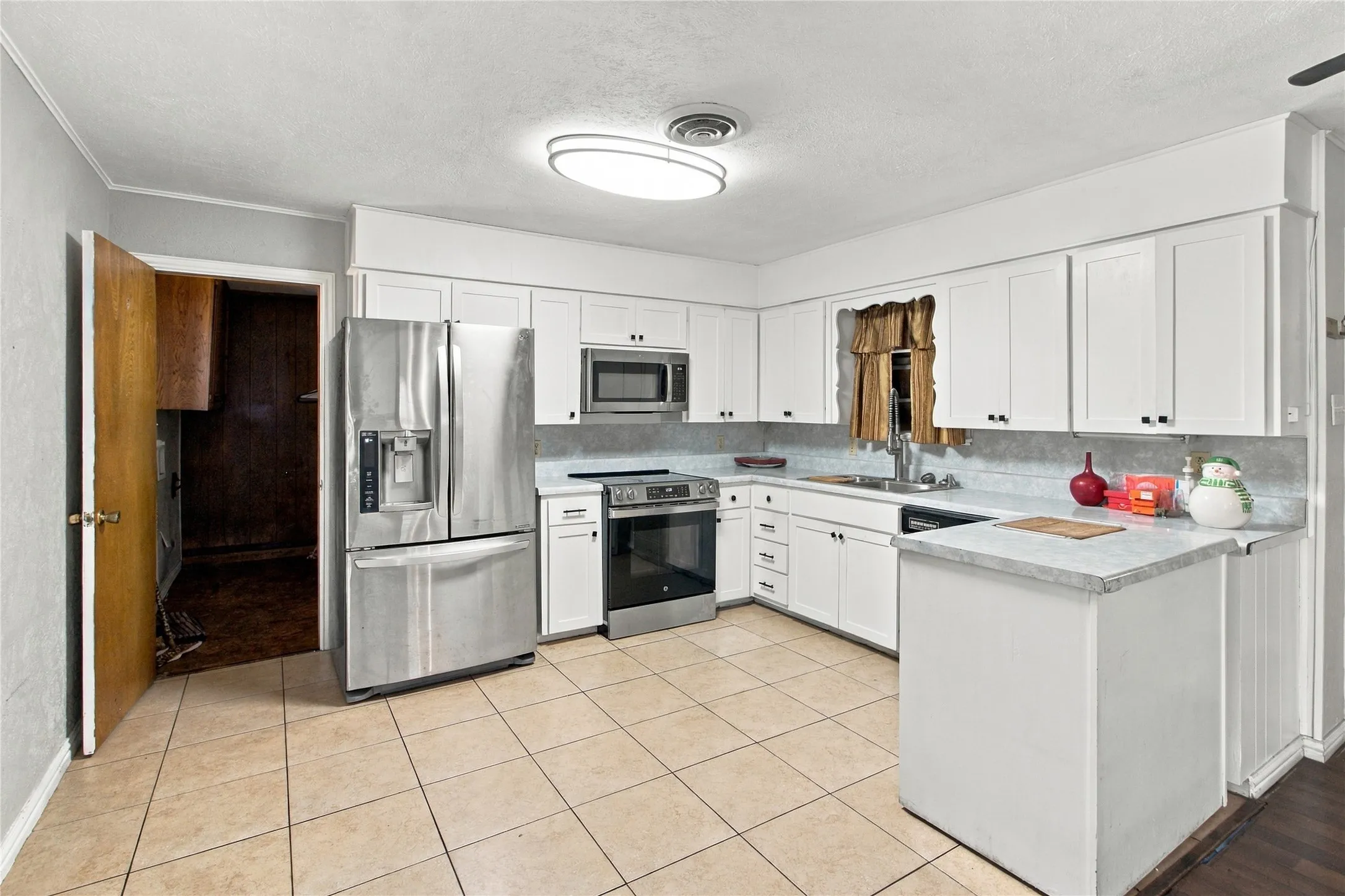 White cabinetry, stainless steel appliances, tile flooring, and a built-in kitchen island