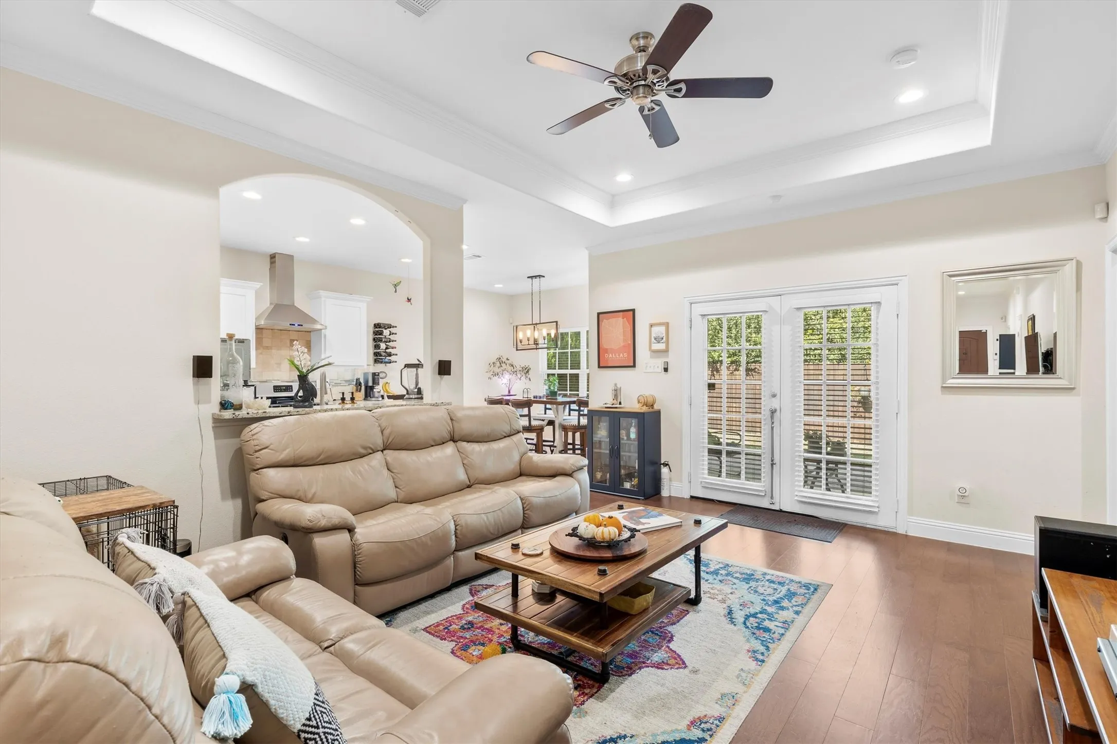 Living area featuring wood-finish flooring, a tray ceiling with a ceiling fan, and recessed lighting