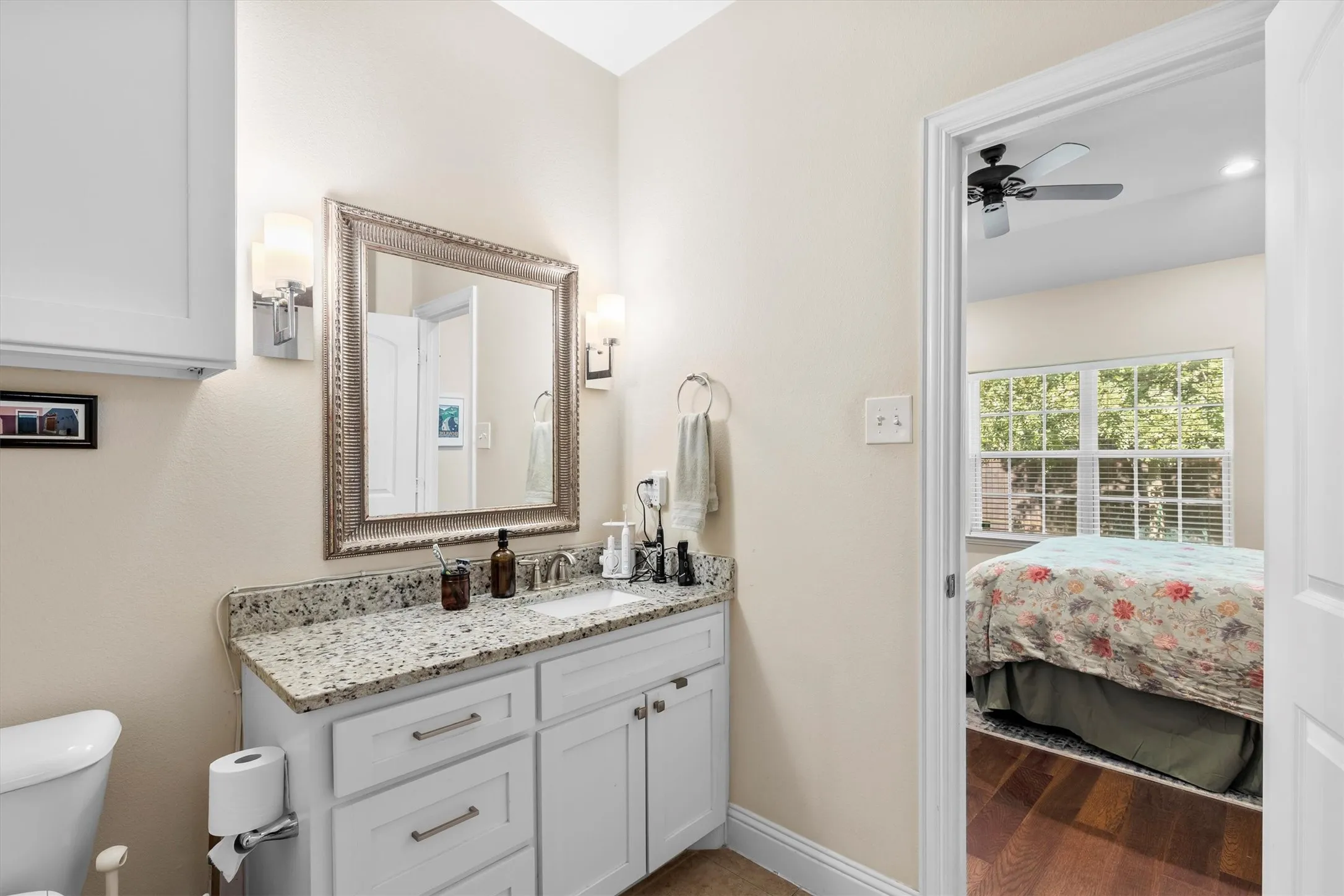 Bathroom vanity featuring a speckled countertop, undermount sink, and a framed mirror with sconce lighting