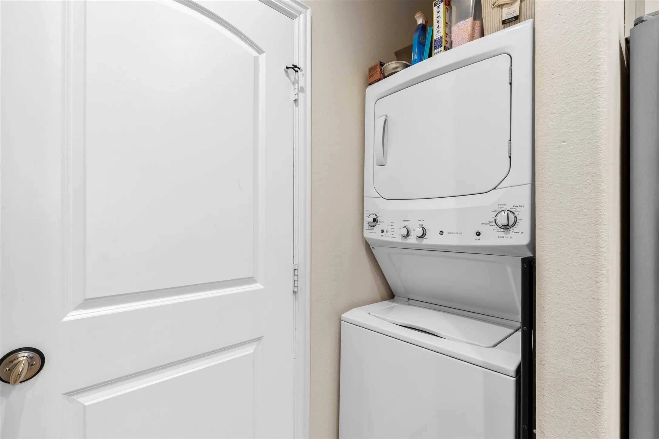 Compact laundry area featuring a stacked washer and dryer unit