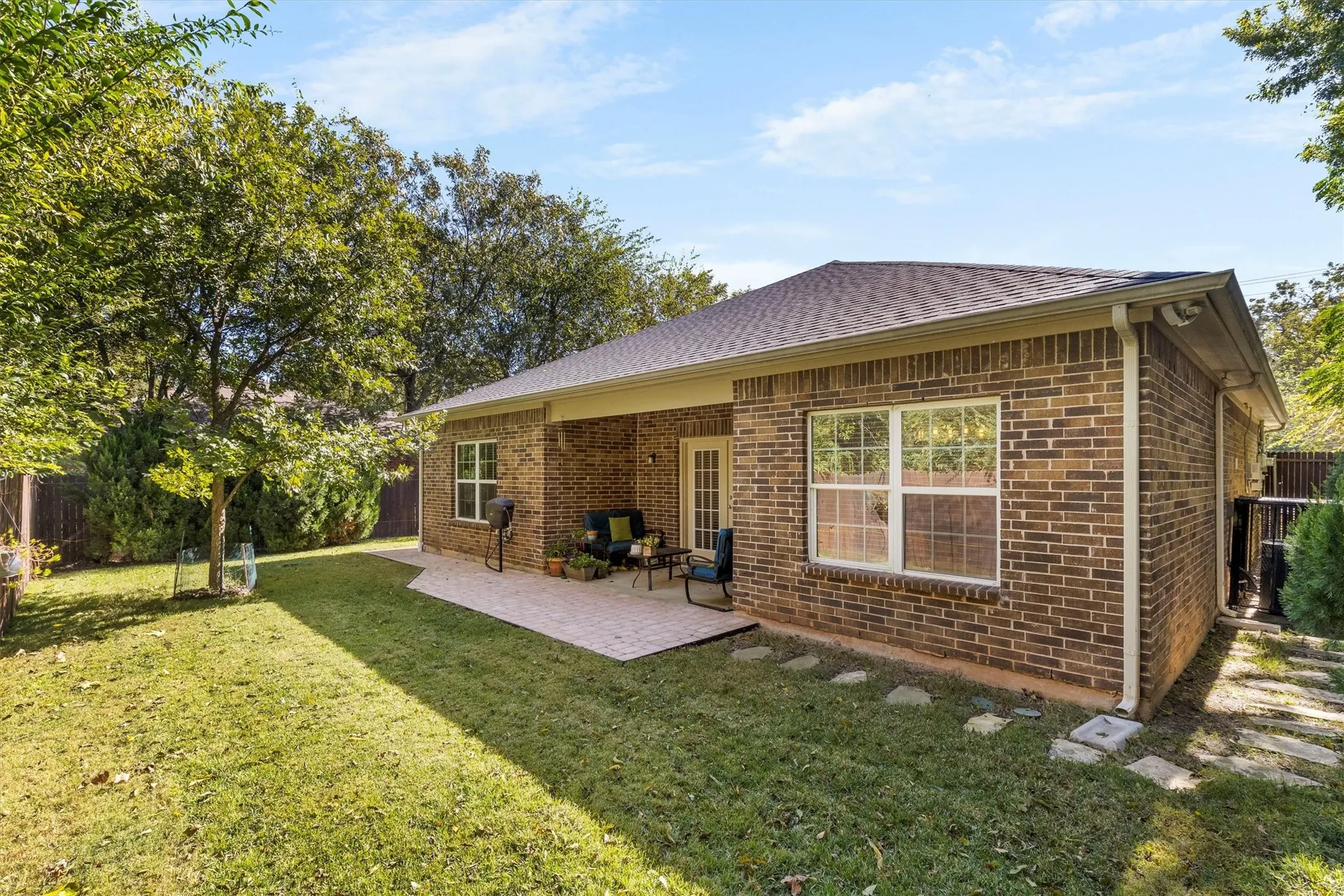 Brick exterior featuring a covered patio, multiple windows, and a shingled roof