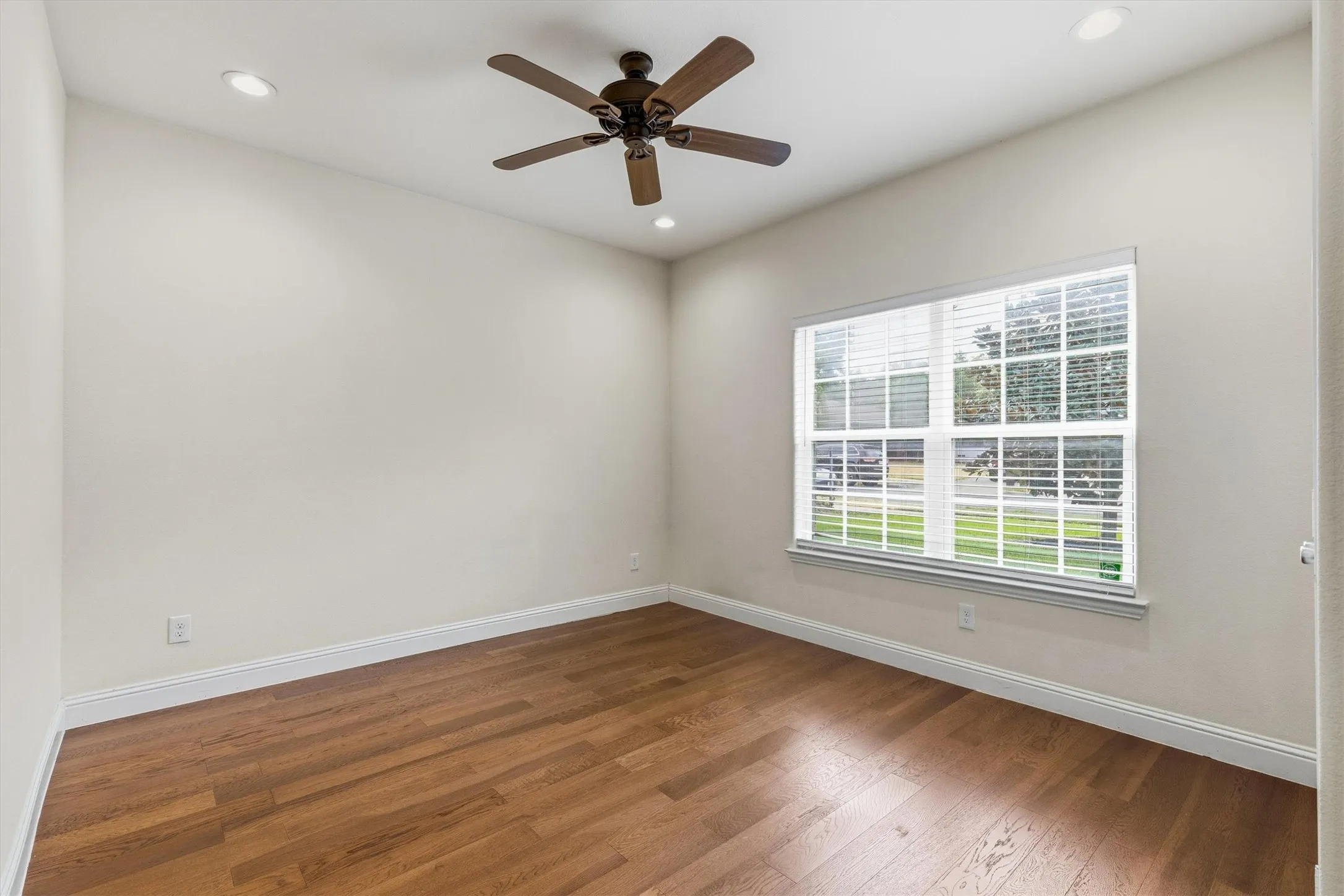 Wood-finish flooring, recessed lighting, ceiling fan, and a double-pane window with white blinds