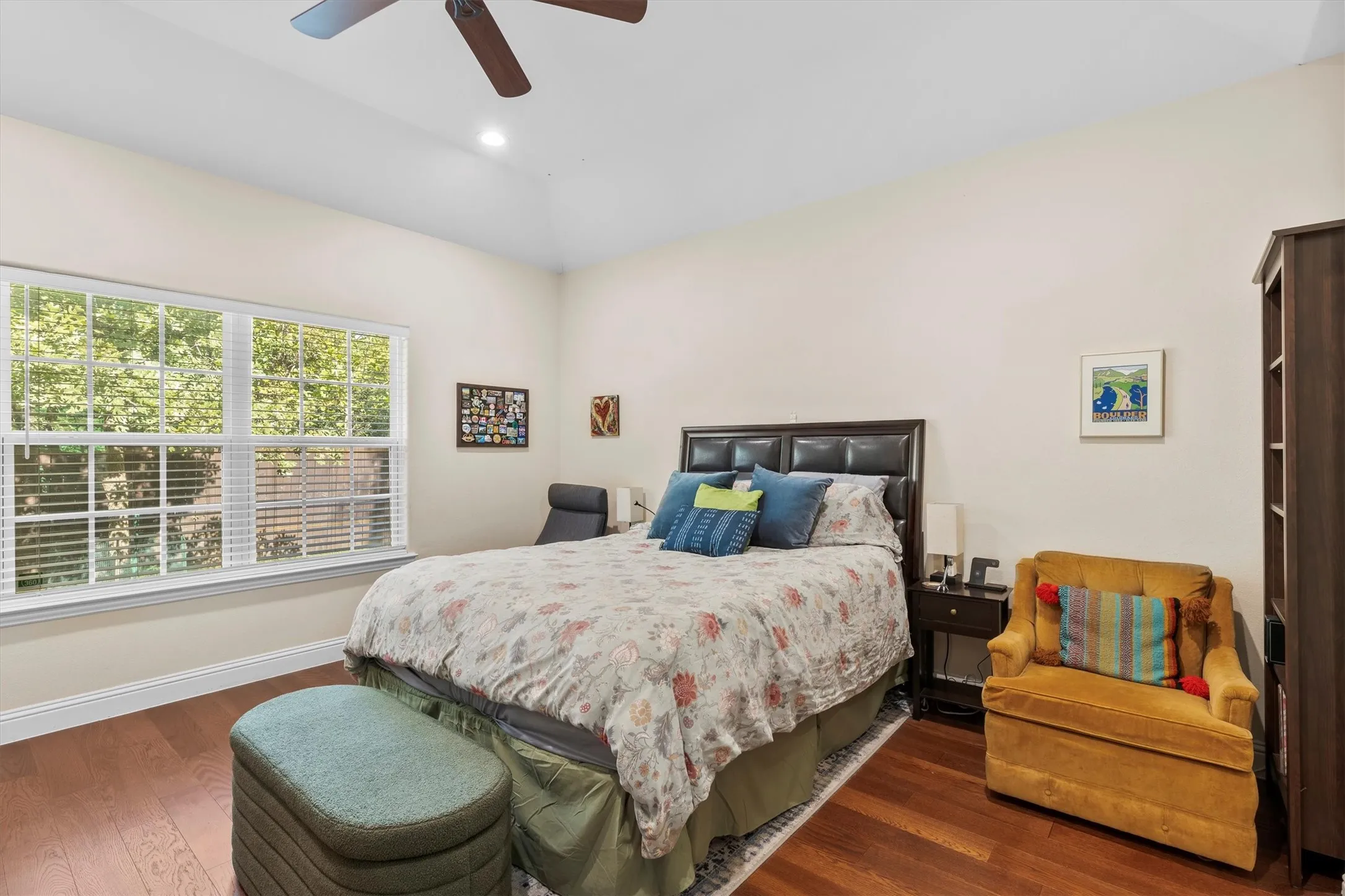 Spacious room featuring wood-finish flooring, a large window with blinds, and a ceiling fan