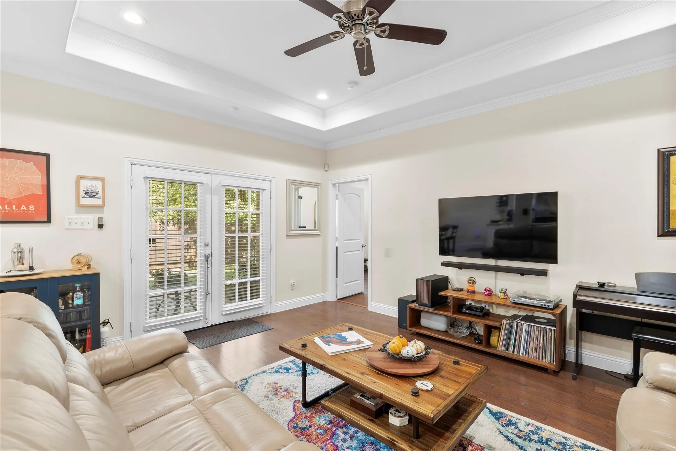Living area featuring rich wood-finish flooring, a coffered ceiling with recessed lighting and a ceiling fan, and double French doors with interior grilles