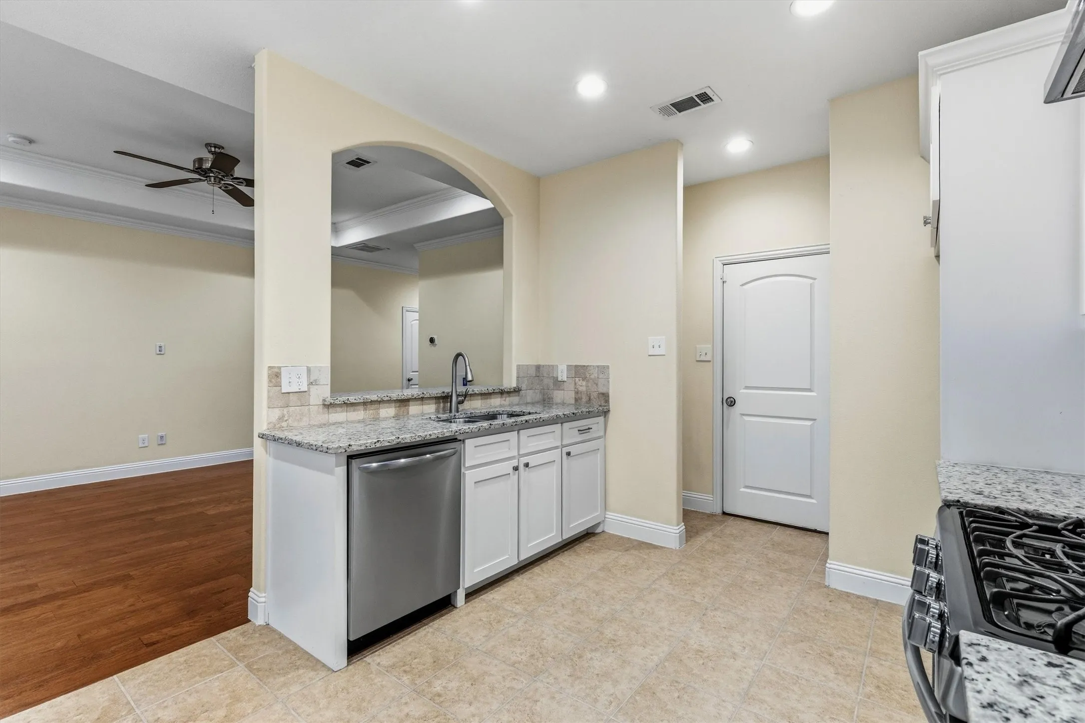 Kitchen featuring granite countertops, stainless steel sink, white cabinetry, and a tile backsplash
