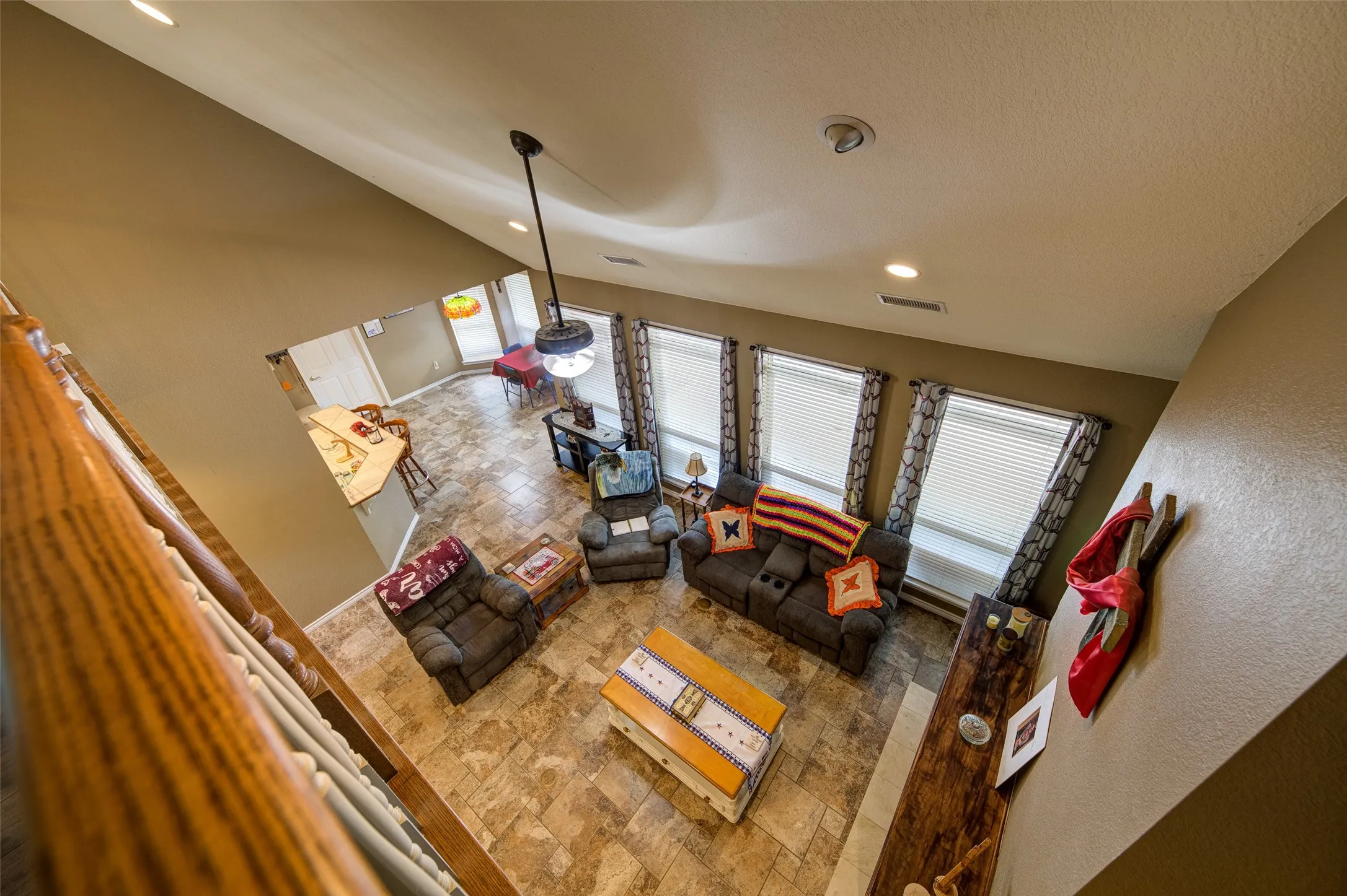 Living area featuring a vaulted ceiling with recessed lighting and a ceiling fan, three windows with blinds, and tile flooring