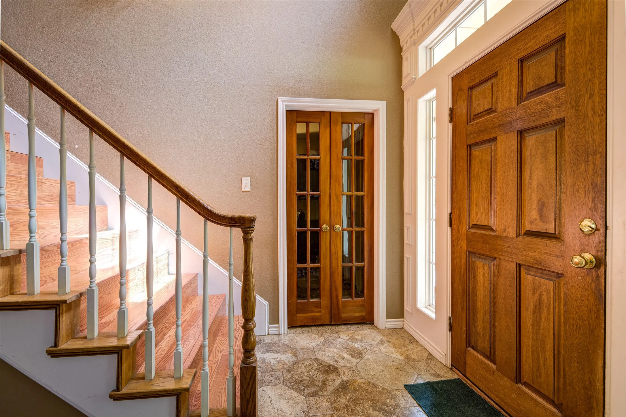 Foyer featuring a paneled wood entry door with brass hardware, sidelight, and transom window