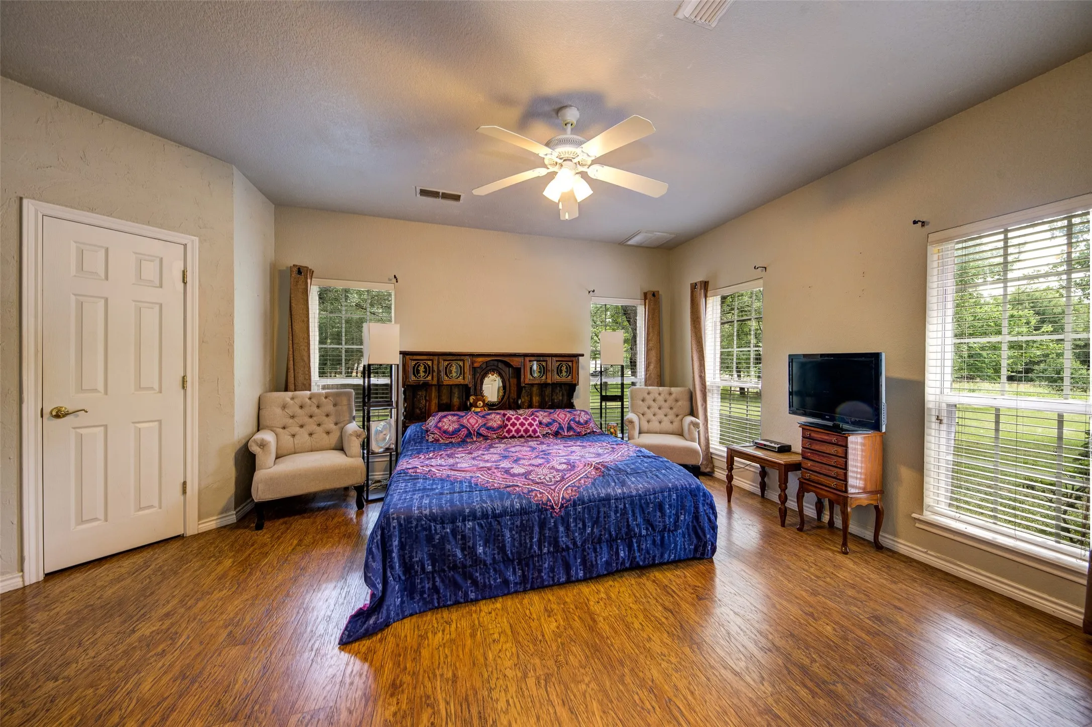 Spacious room featuring wood-finish flooring, a vaulted ceiling, and a ceiling fan with integrated lighting