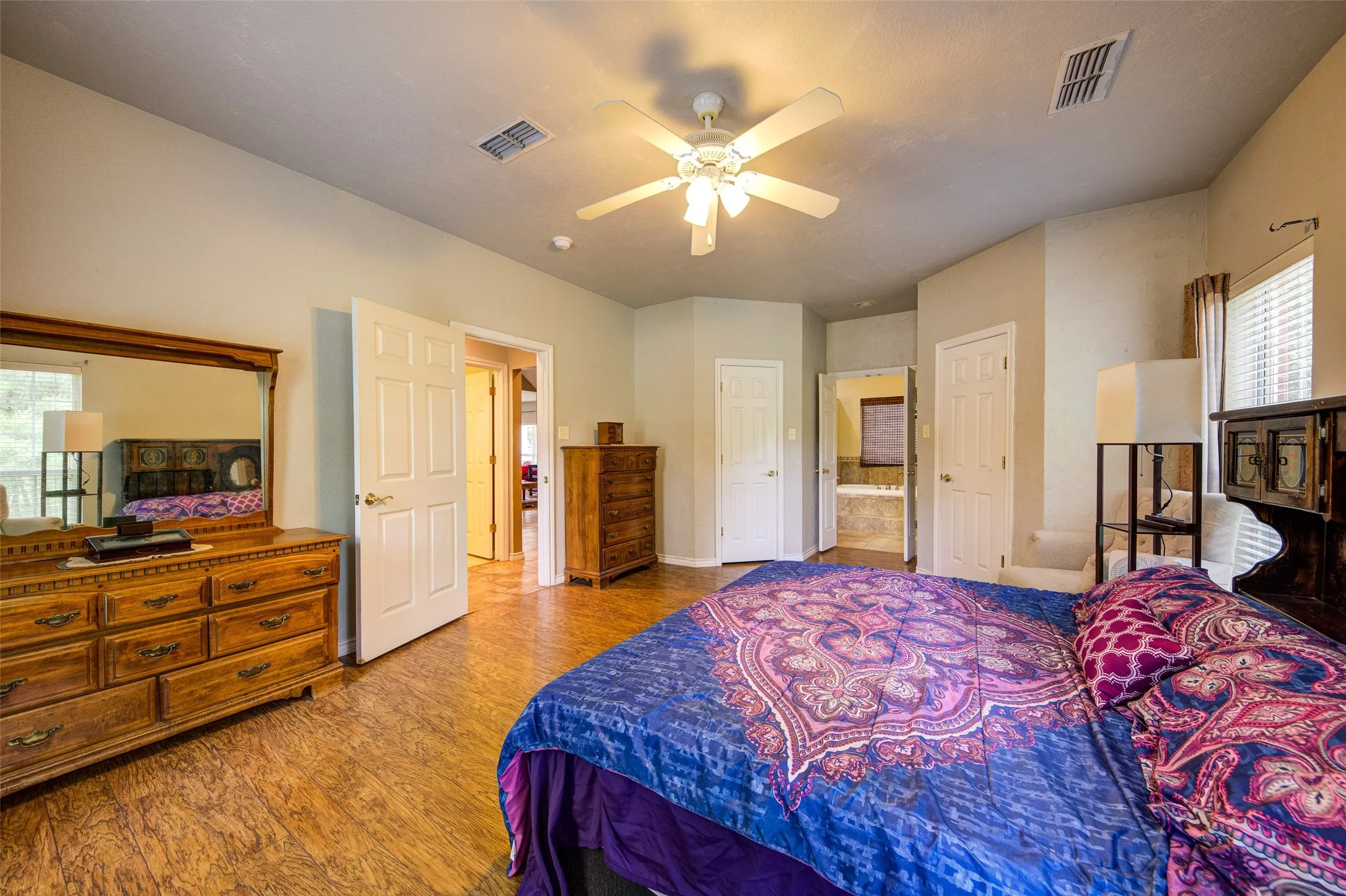 Spacious room featuring wood-finish flooring, light-toned walls, and a ceiling fan with integrated lighting