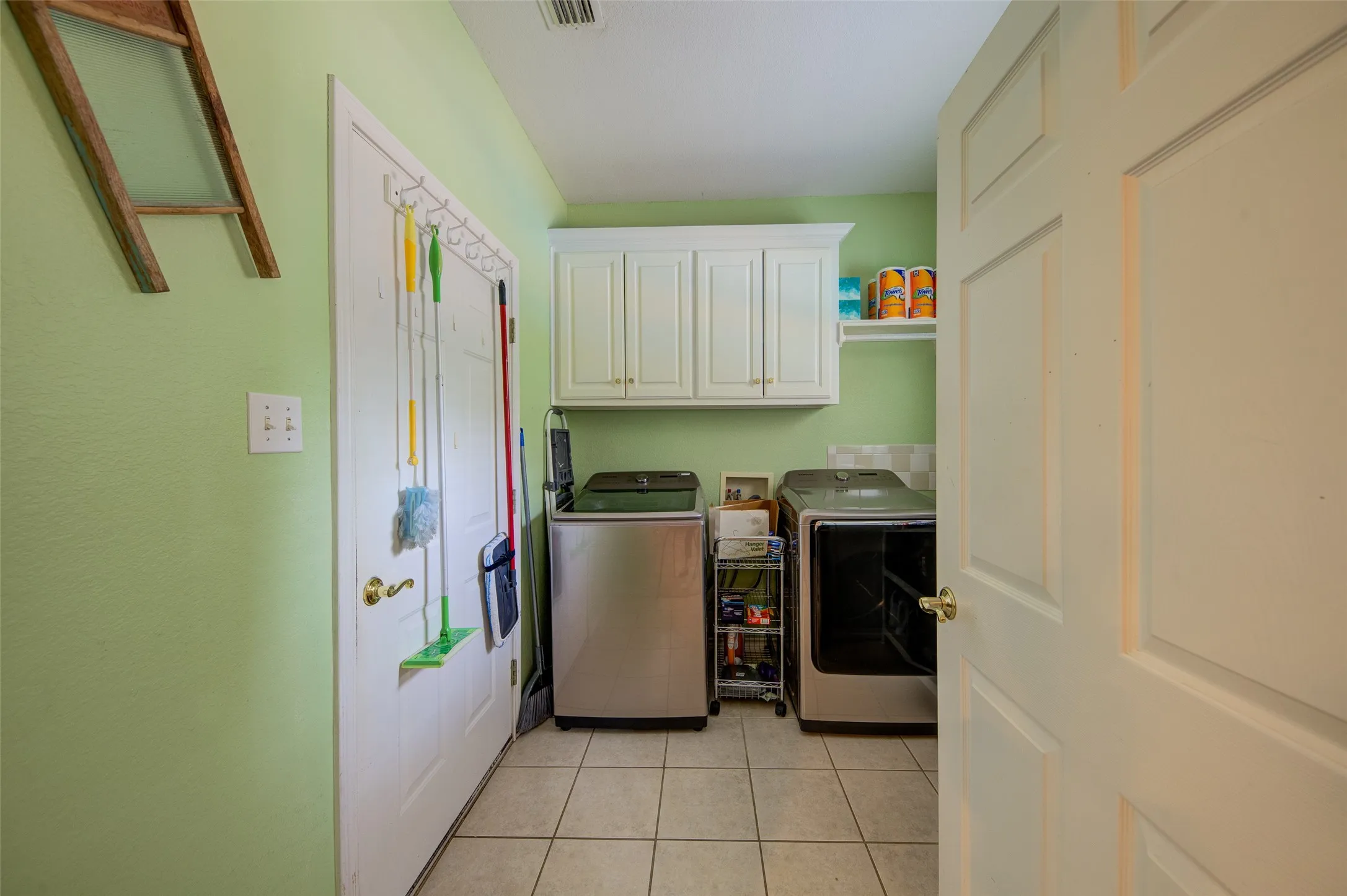 Laundry area featuring a tiled floor, overhead cabinetry, and a wall-mounted shelving unit