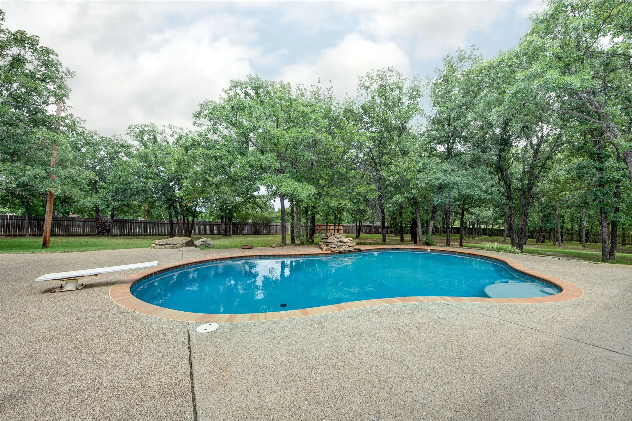 Custom-shaped pool with a diving board and integrated rock waterfall feature