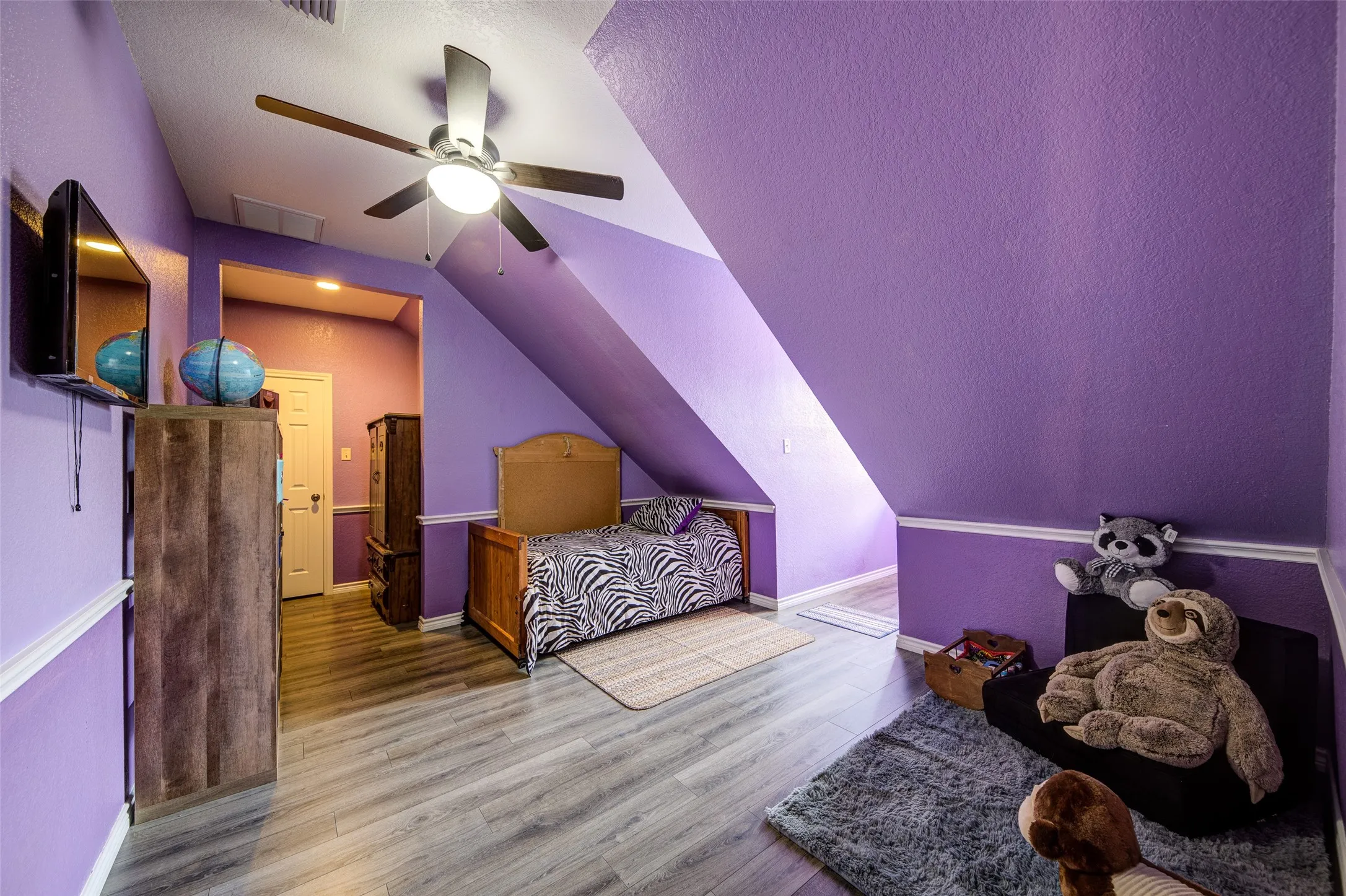 Room featuring wood-finish flooring, a ceiling fan with integrated lighting, and a built-in wall shelf