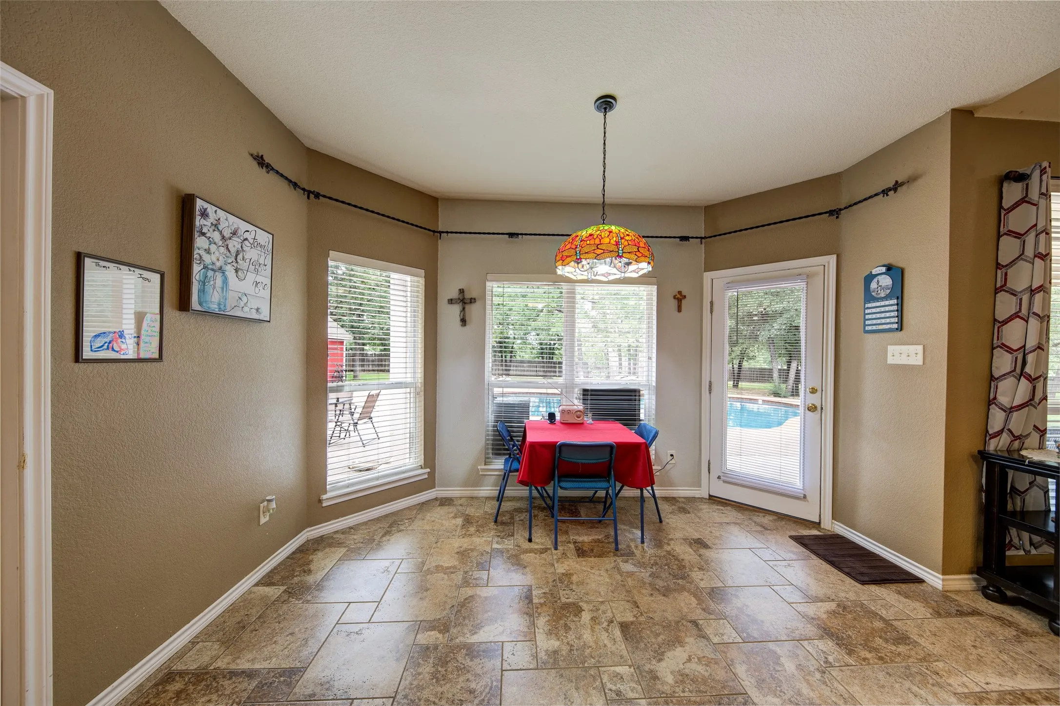 Tile flooring throughout a dining area with a glass-paned door opening to a patio and pool