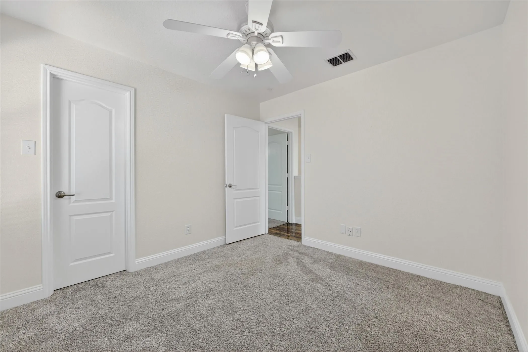 Bedroom Four featuring light gray carpet, white walls, and a ceiling fan with light kit