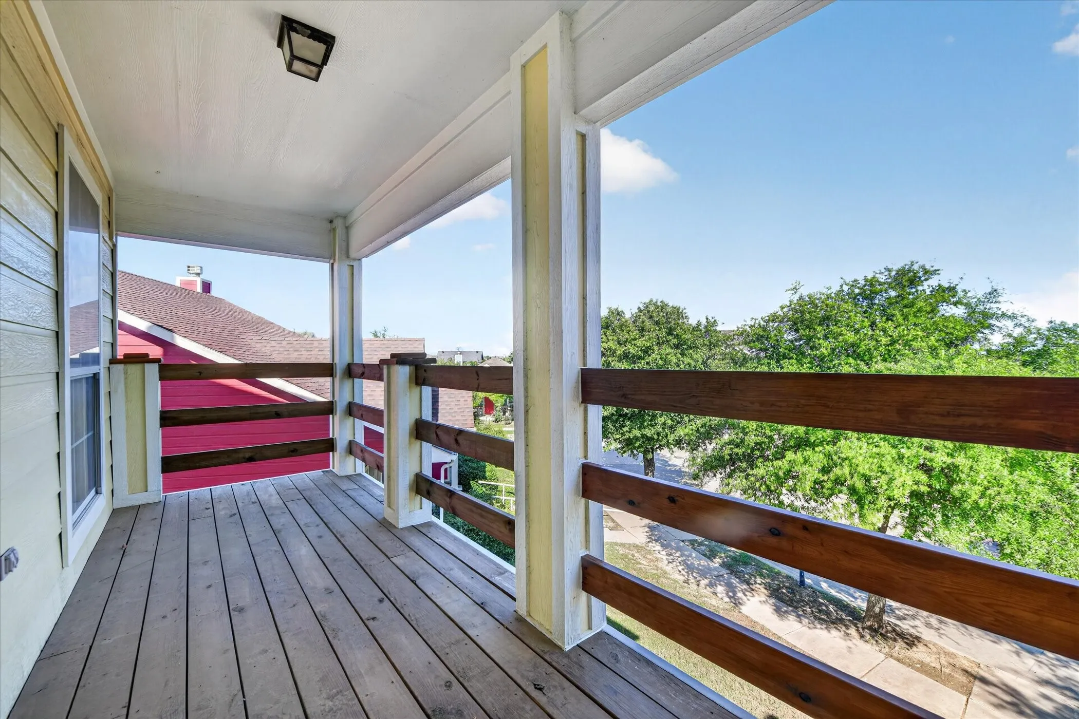 Covered balcony featuring wood-finish flooring and a stained wood railing
